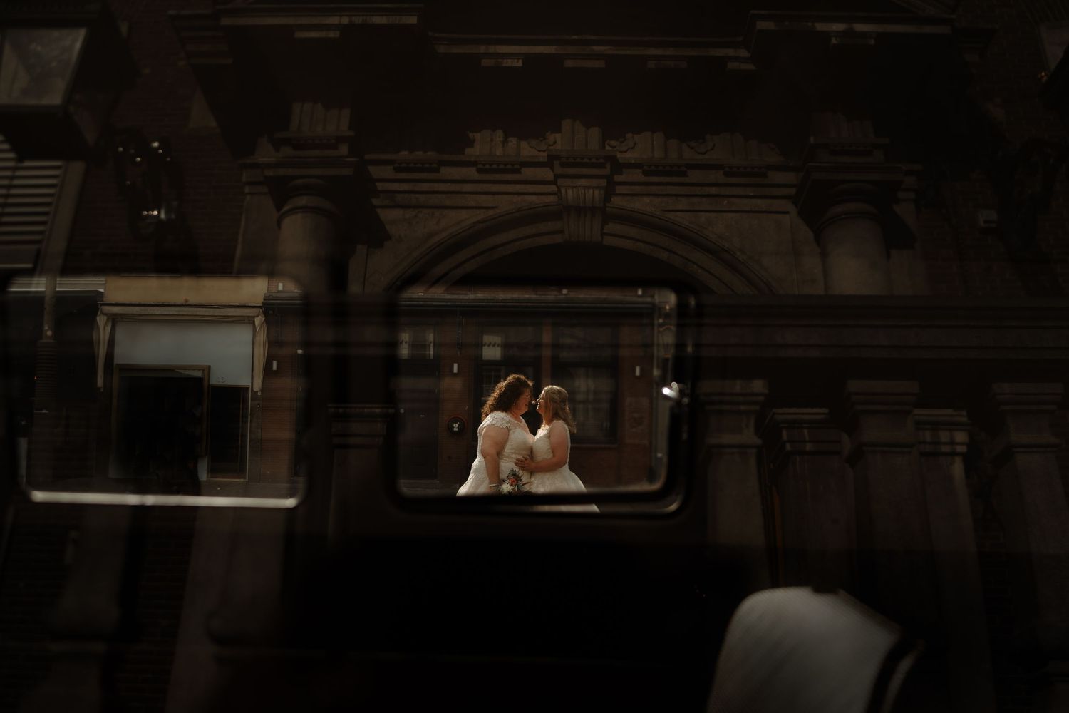 A romantic couple framed through an architectural window at dusk.