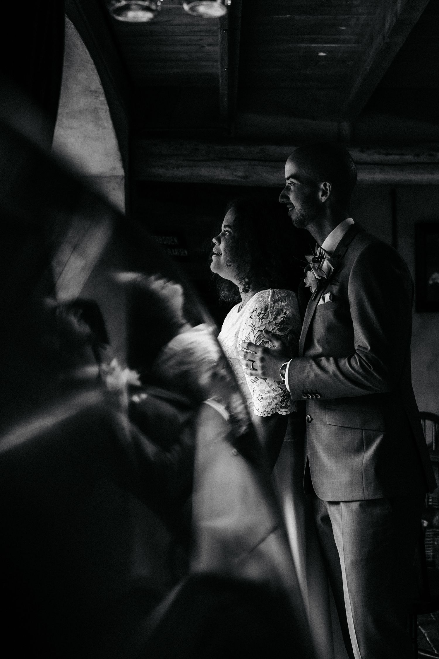 A dramatic black and white wedding portrait showing a tender moment in moody lighting.