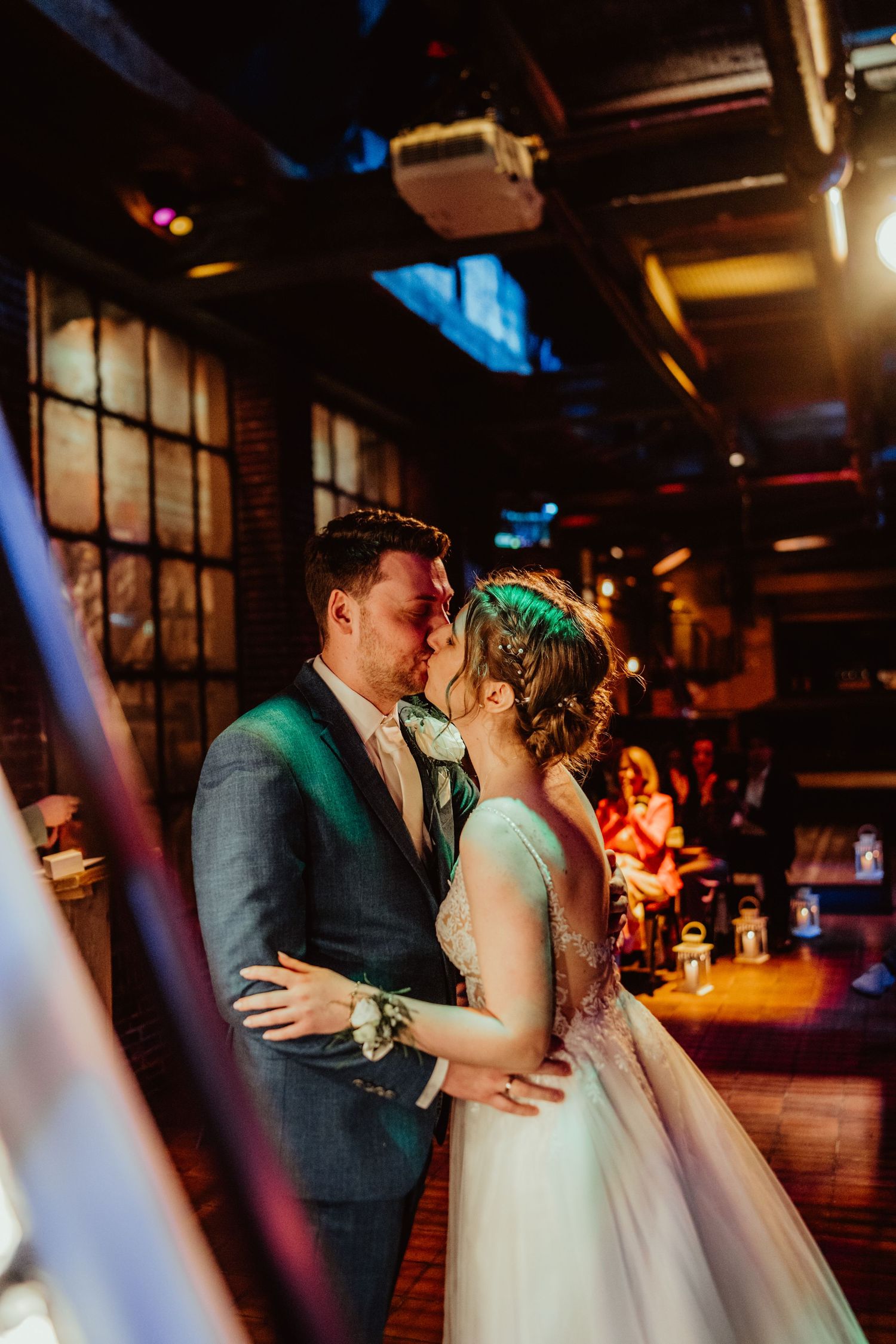 Romantic first dance moment under moody lighting at indoor wedding reception venue.