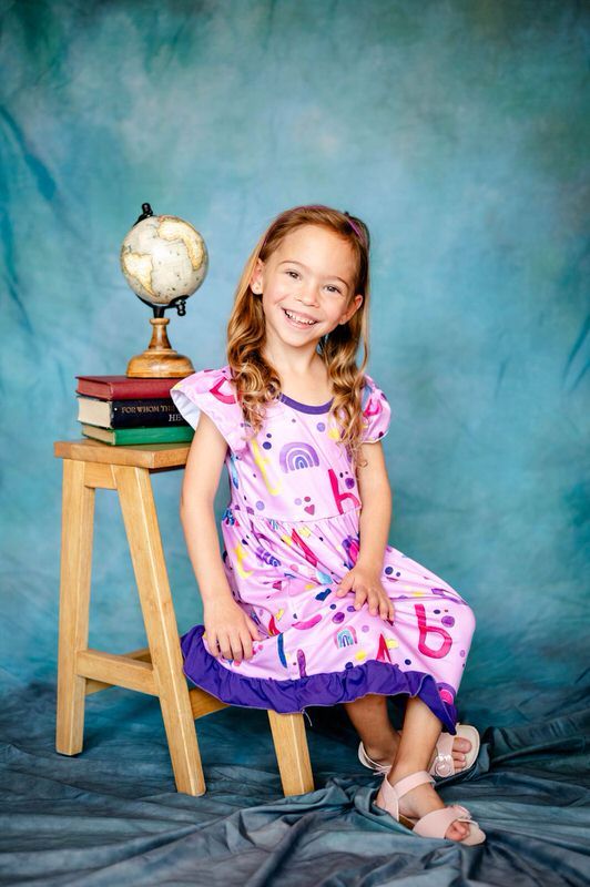 Cute smiling preschooler during her school pictures by an affordable Jacksonville preschool photographer with her own equipment