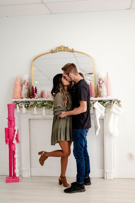 Couple kissing at a pink Christmas decorated studio in Jacksonville FL