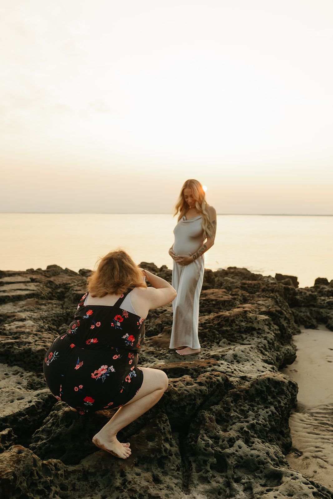 Behind-the-scenes shot of Jessica Life Photography capturing a maternity photoshoot at Jacksonville beach during golden sunrise hour.