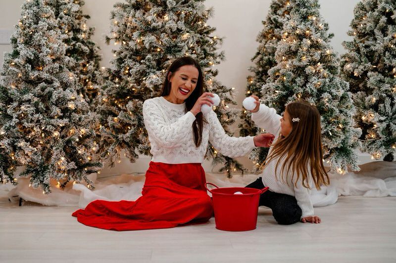 Christmas family photo at a Jacksonville Studio of mom and daughter playing with white cotton snowballs