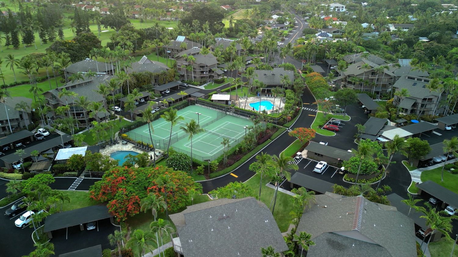Aerial view of resort complex with tennis courts, pool, and parking area.