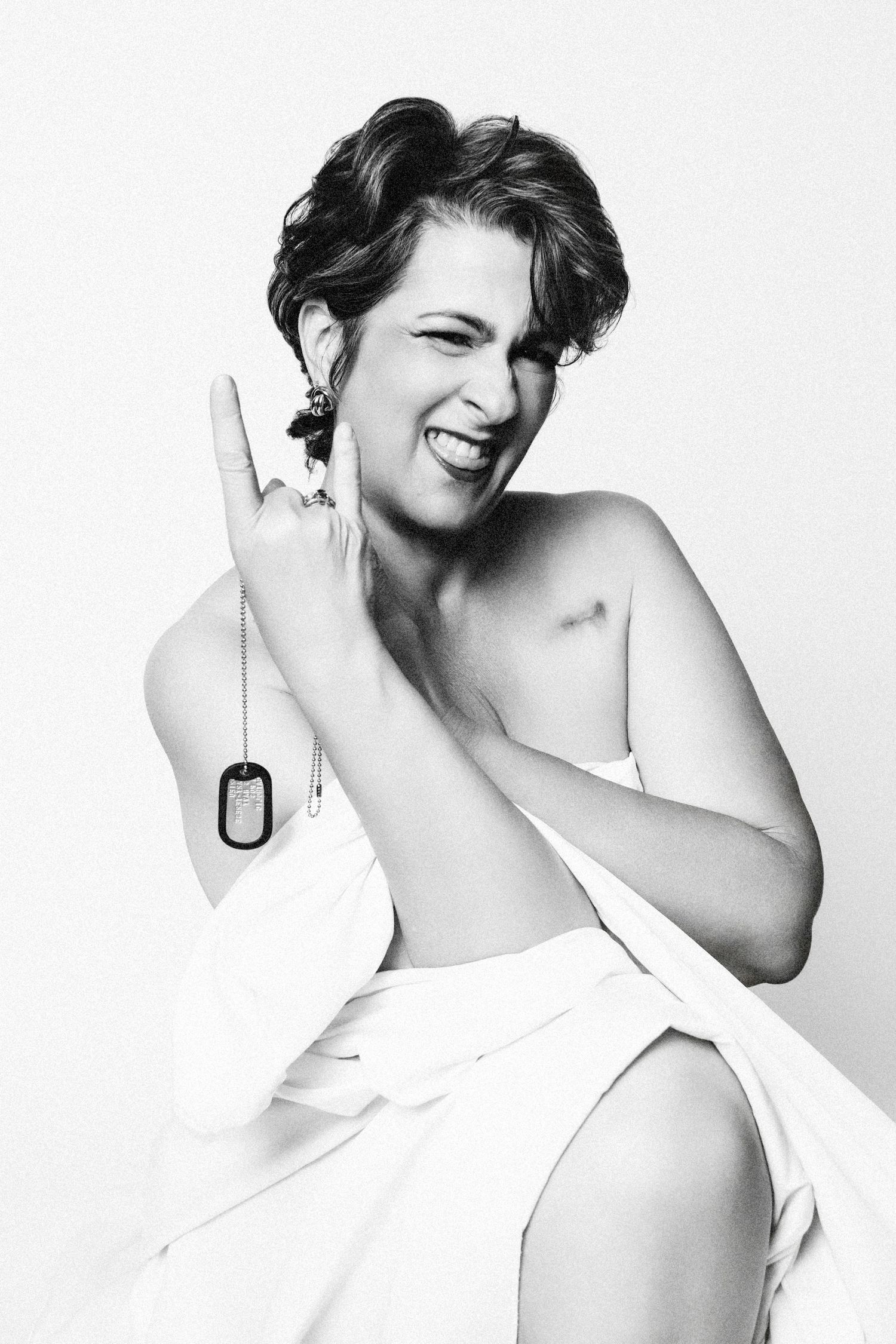 Playful studio portrait of woman wrapped in white fabric making peace sign.