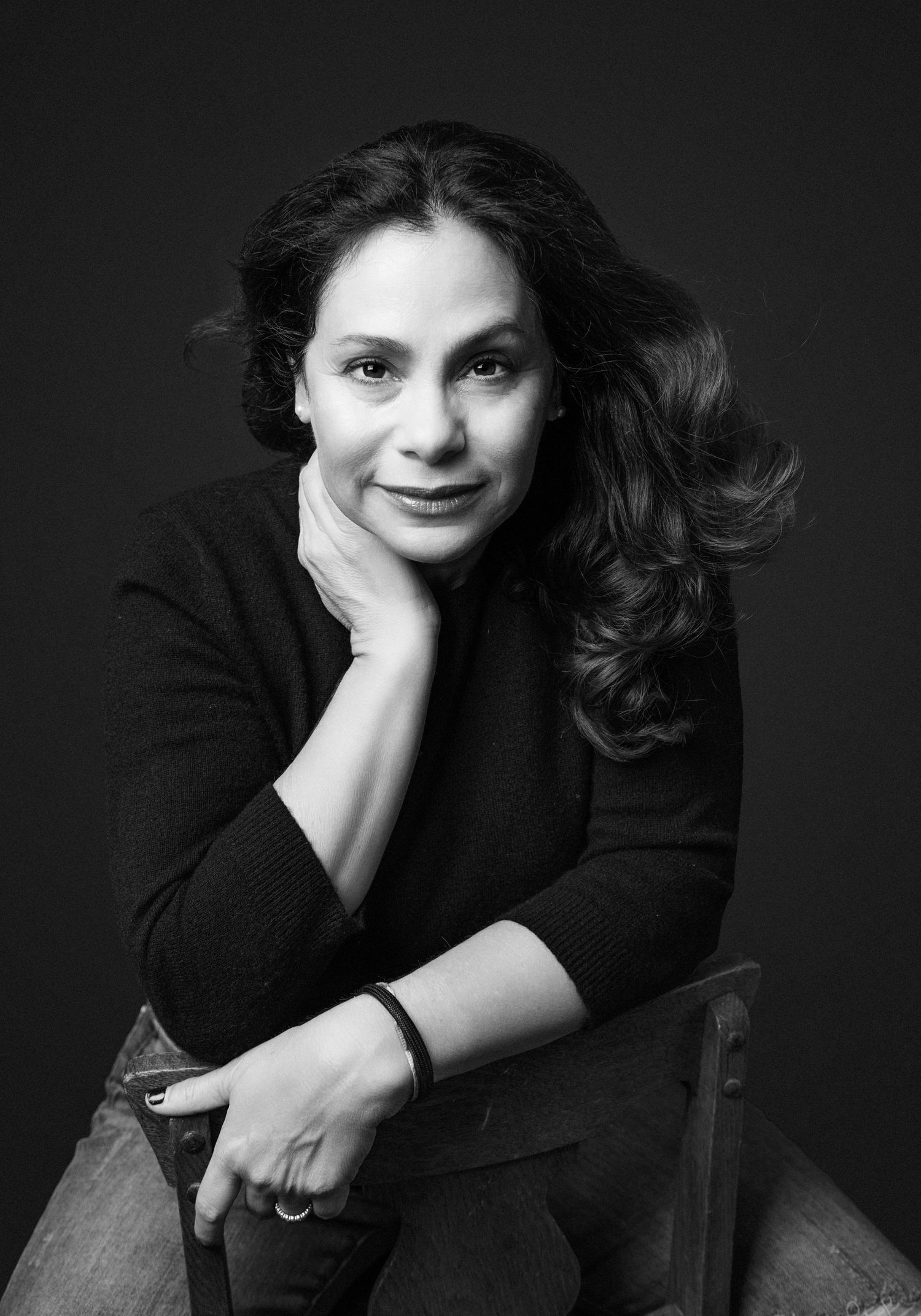 Classic black and white portrait of person in black sweater resting hand on chin.