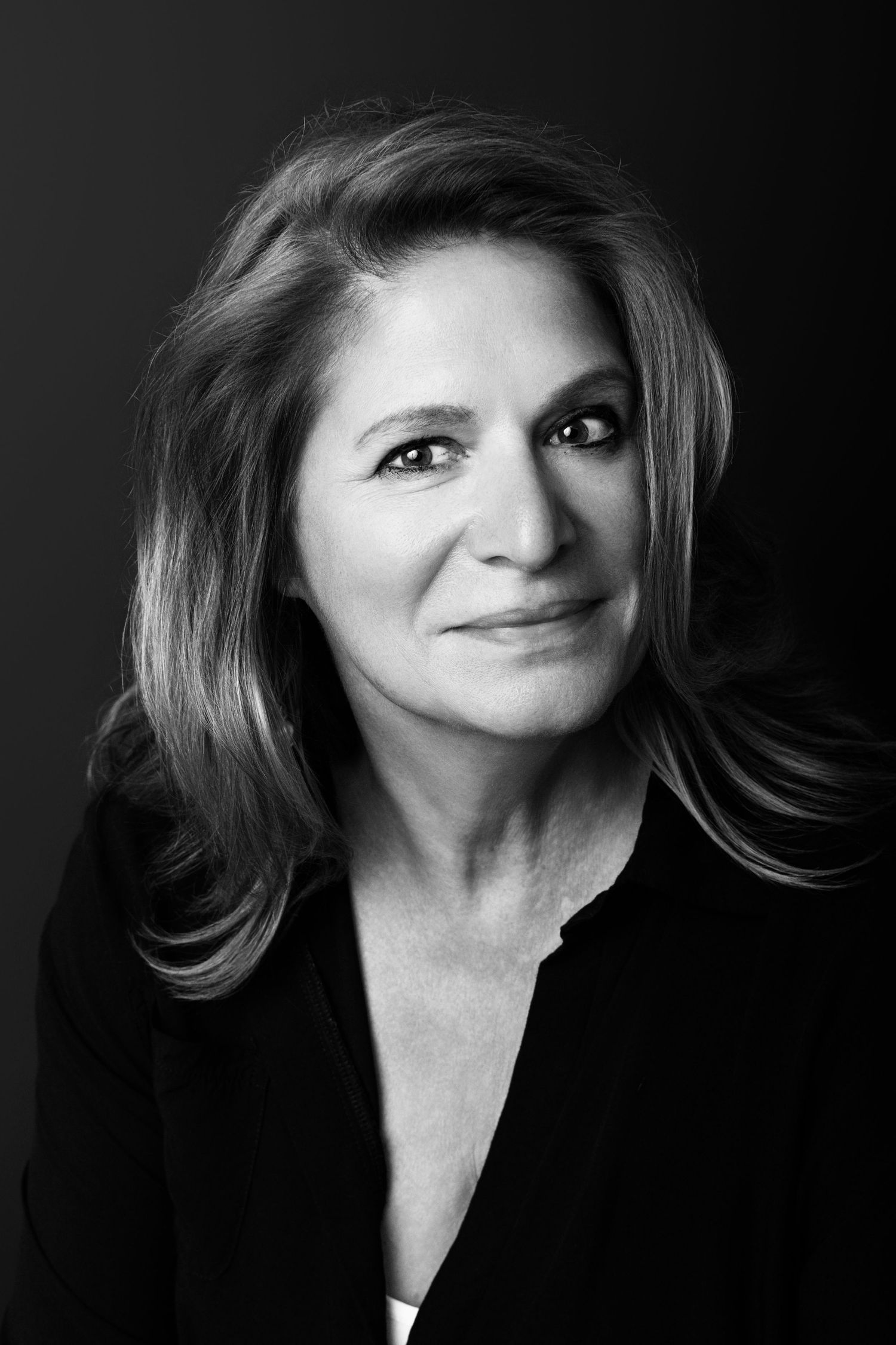 A professional black and white headshot portrait against dark background with dramatic side lighting.