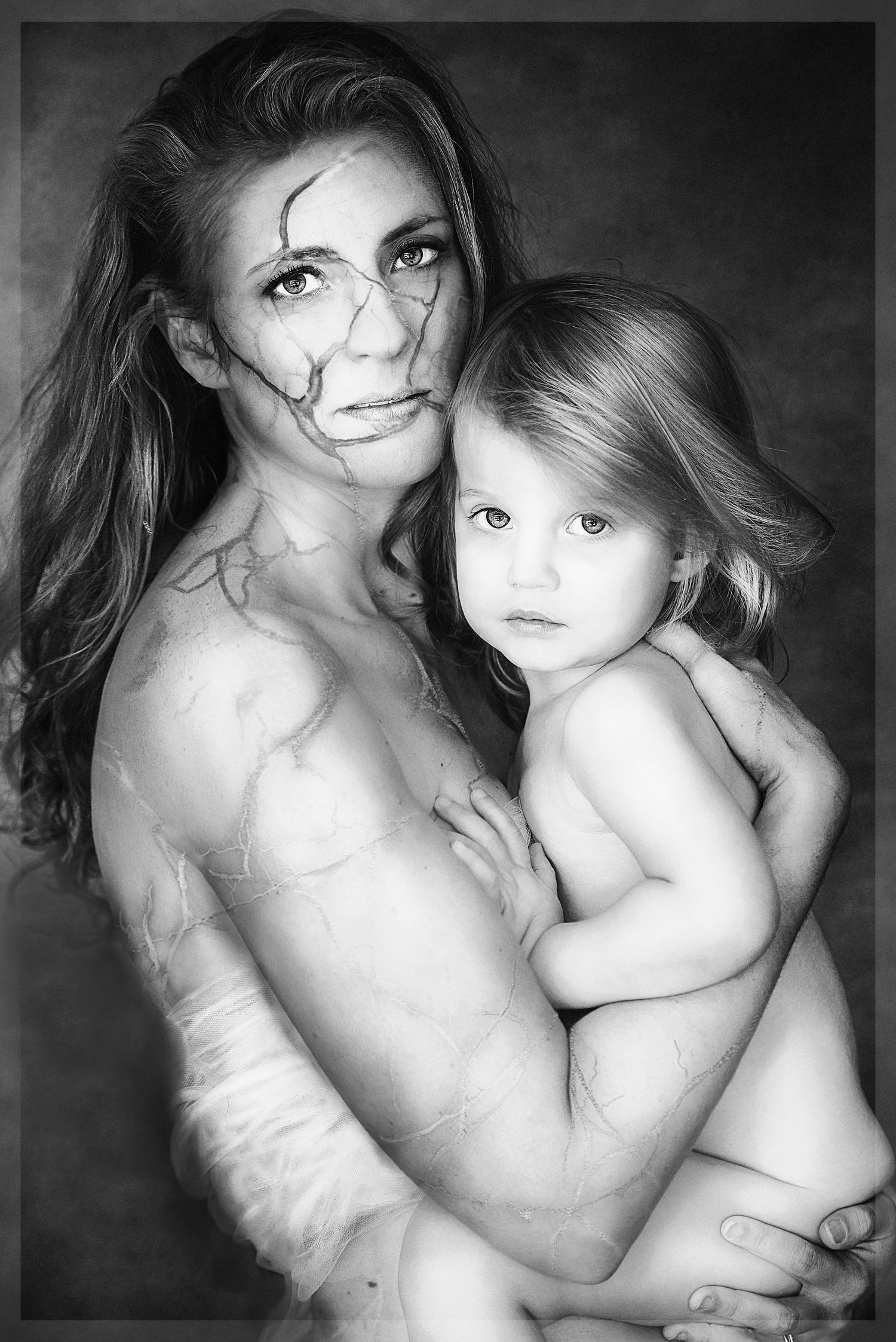 Intimate black and white portrait of mother and child in artistic nude style.
