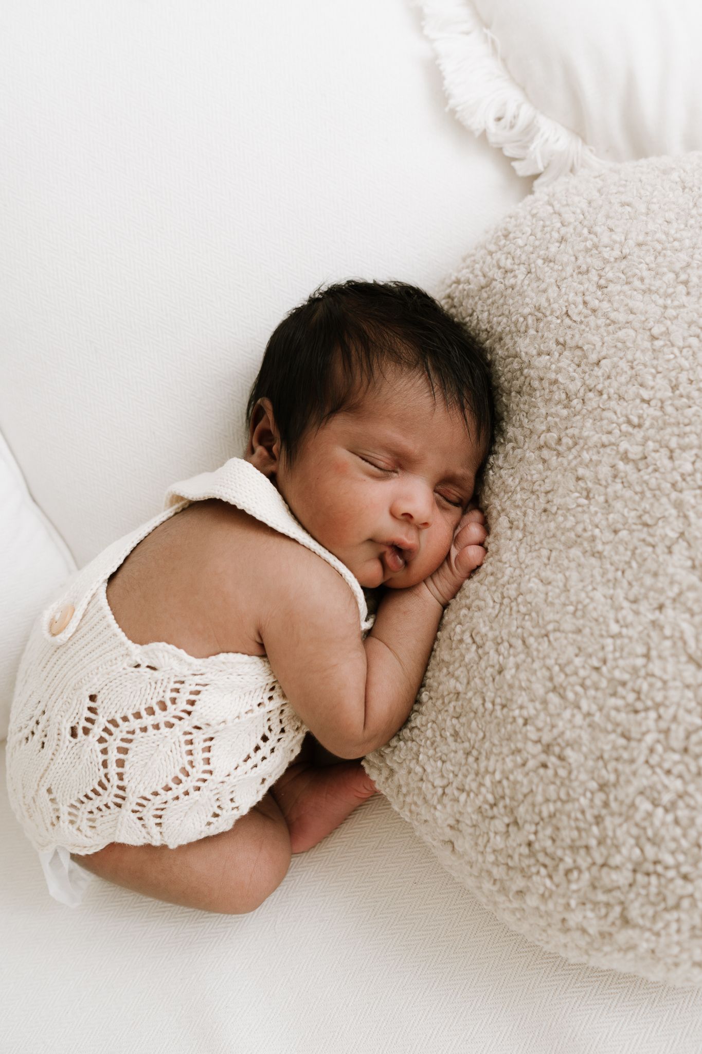 newborn sleeping baby wrapped in white blanket during studio session in Auckland