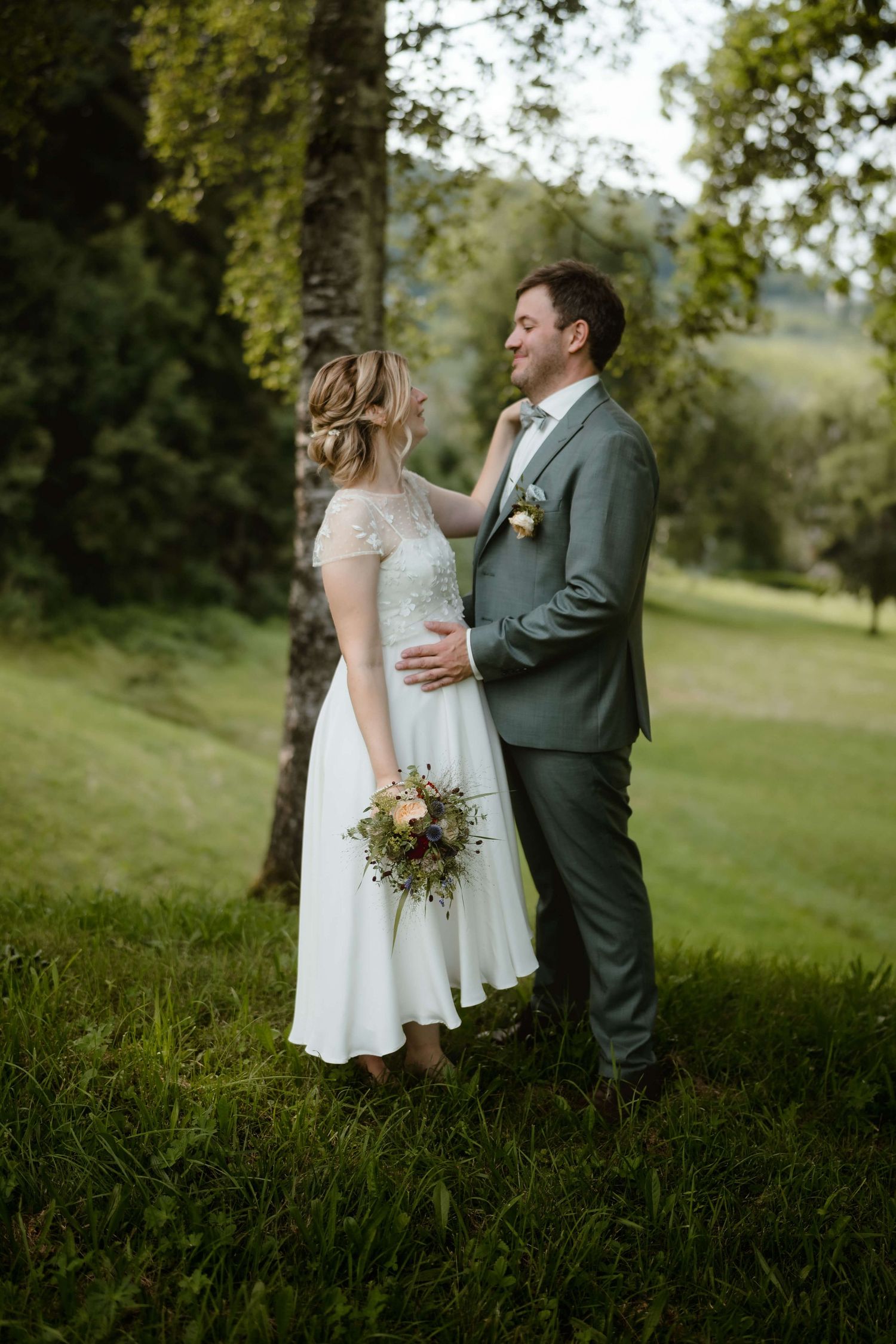 Braut und Bräutigam mit Blumenstrauß auf einer Wiese – echte Hochzeitsmomente in Vorarlberg, festgehalten von NuMa Fotografie.