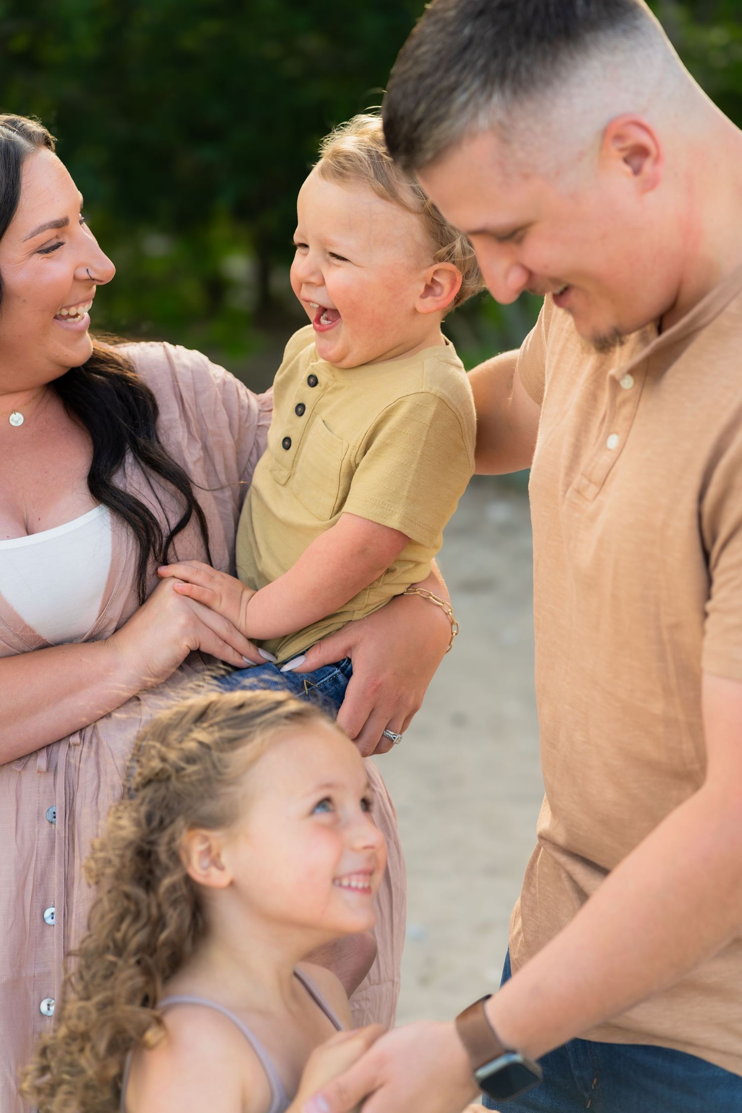A happy family sharing joyful laughter together outdoors during a bright summer day.