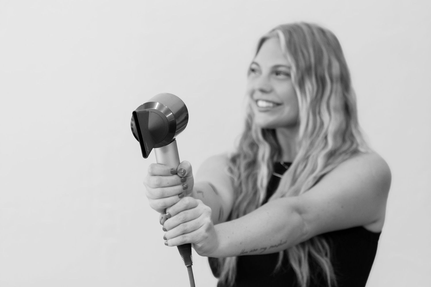 Black and white photo of someone playing maracas while smiling against a light colored background.