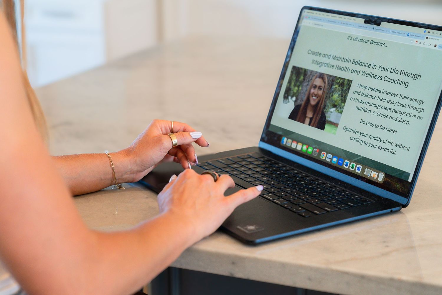 Hands typing on a MacBook laptop keyboard showing a website article on the screen.