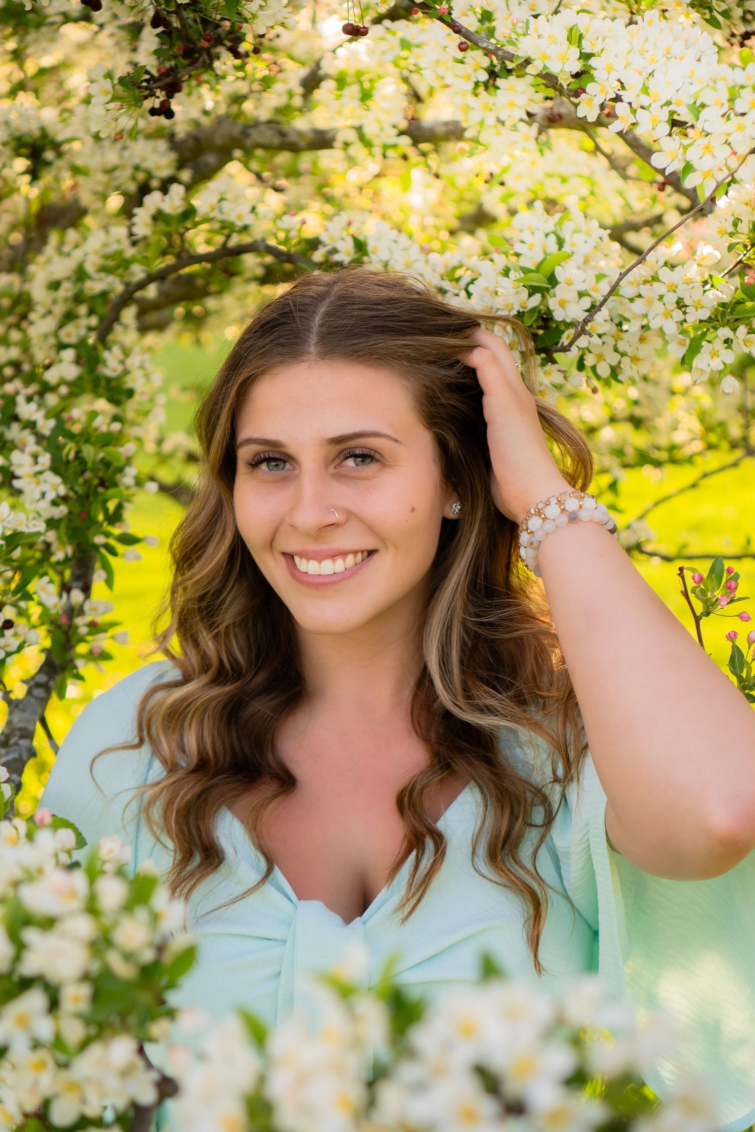 Beautiful spring portrait surrounded by delicate white cherry blossoms and soft natural lighting.