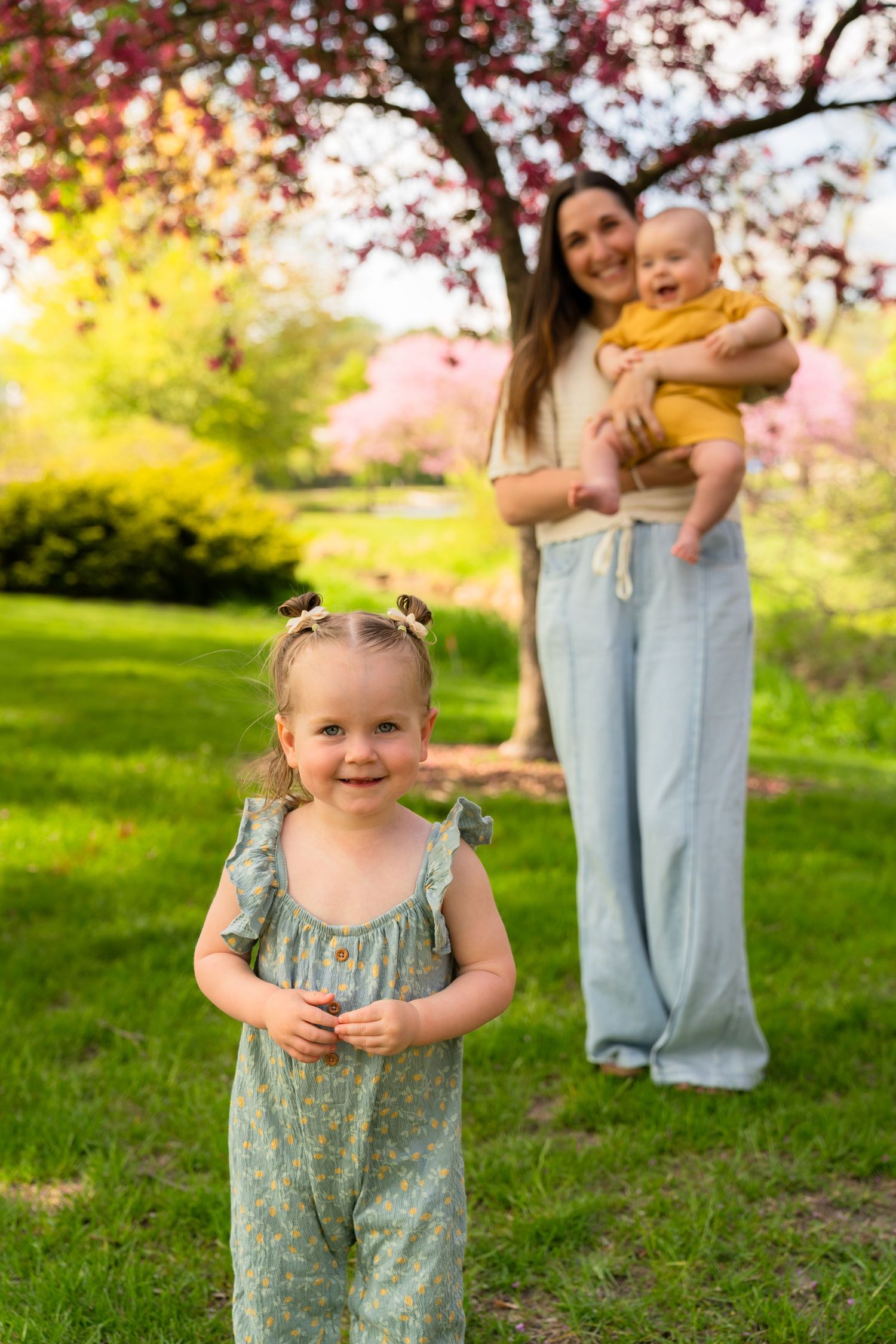 Springtime family portrait in a blooming garden with soft pink cherry blossoms and golden sunlight.