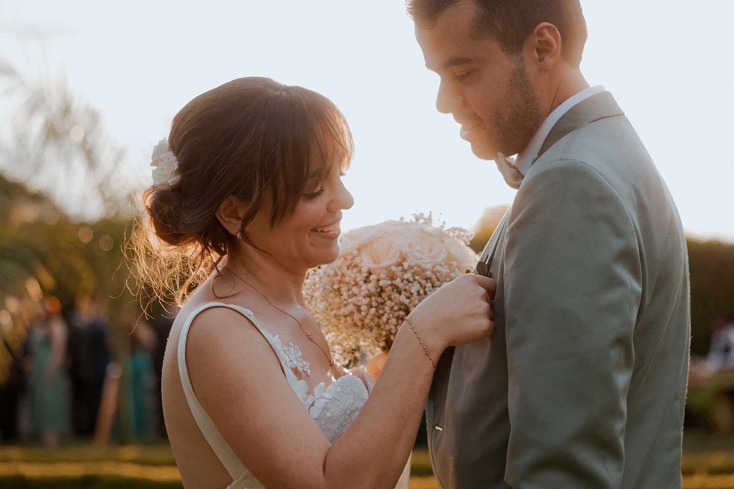A tender wedding moment captured at golden hour as the couple embraces while holding a delicate bouquet.