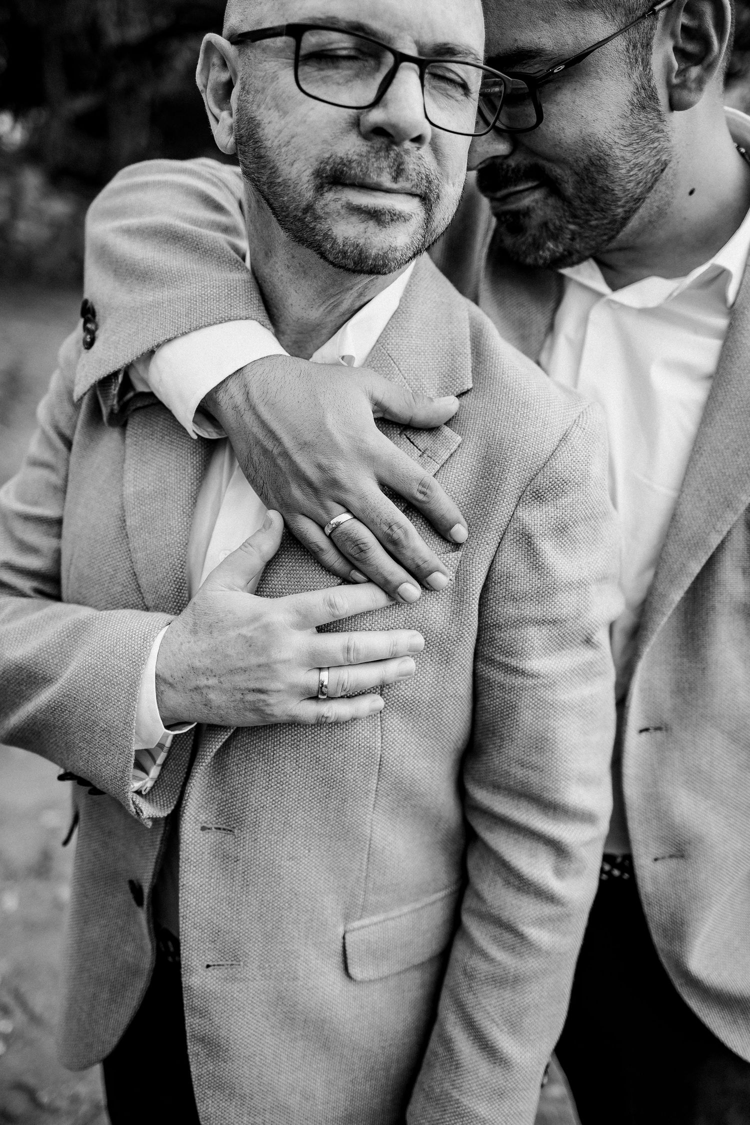 Two people in light suits share an intimate embrace.