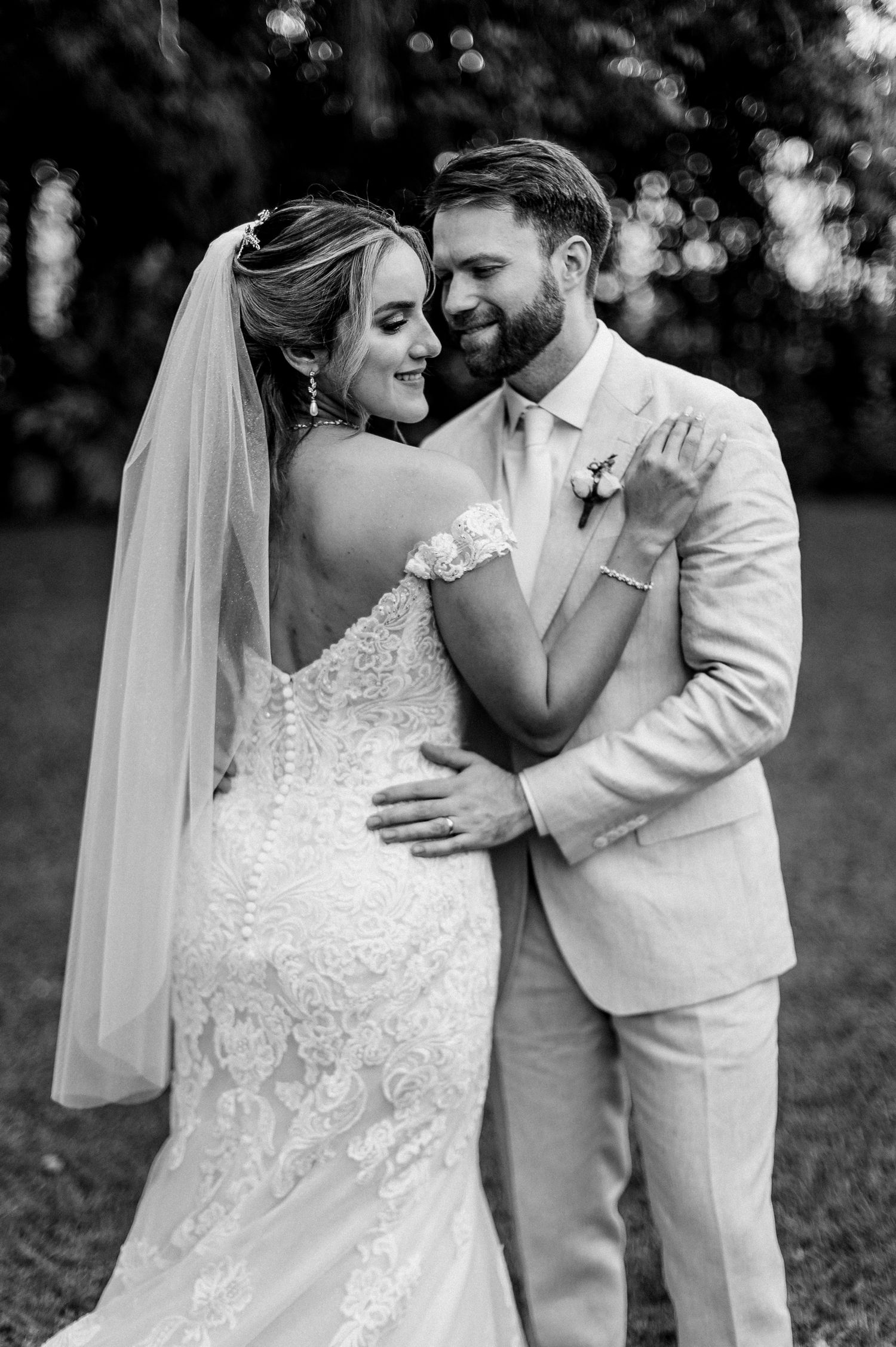 A black and white portrait of newlyweds sharing an intimate dance moment in their elegant wedding attire.