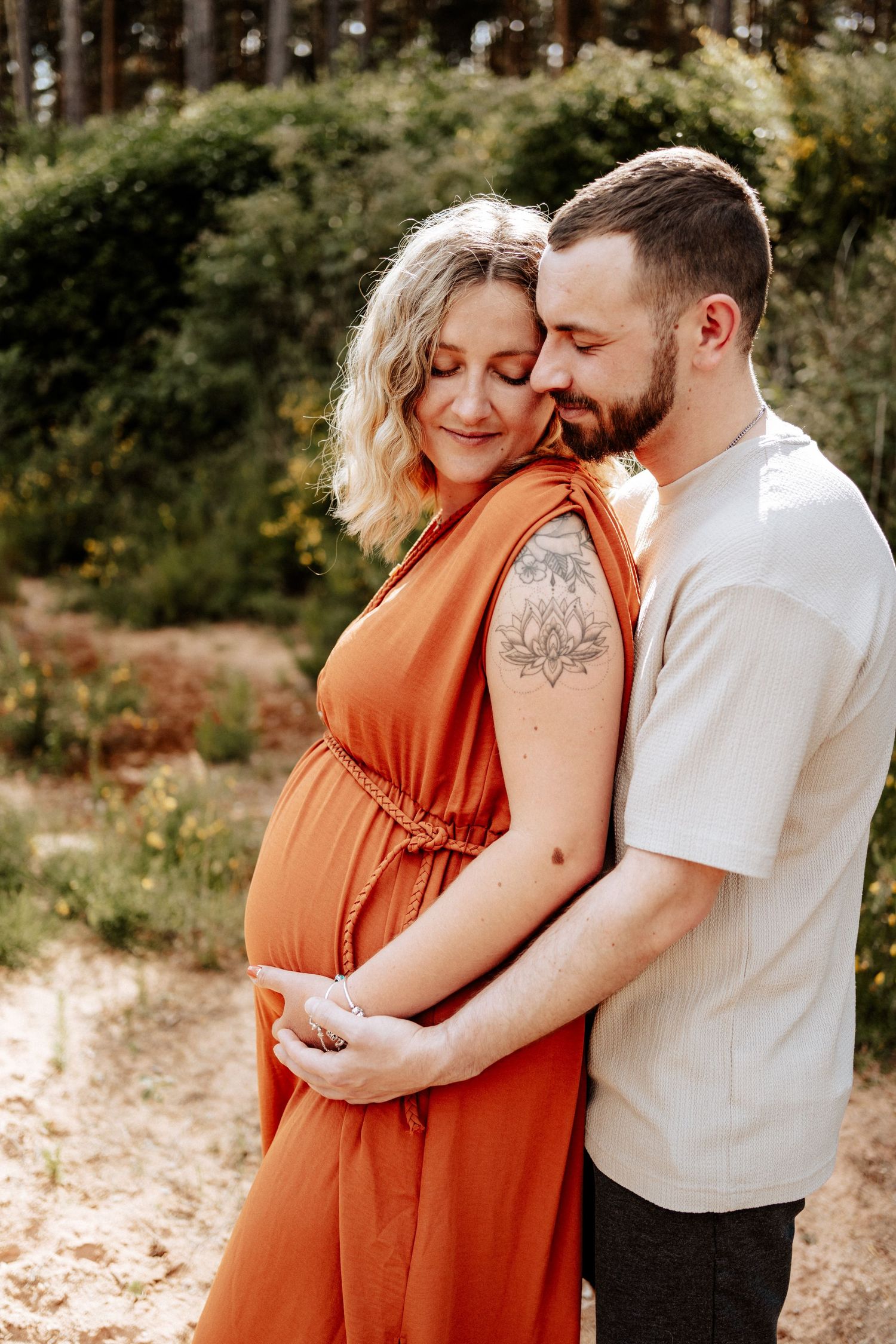 Werdende Eltern umarmen sich liebevoll im Sonnenlicht - Babybauch-Shooting in der Natur zwischen Roth und Allersberg.