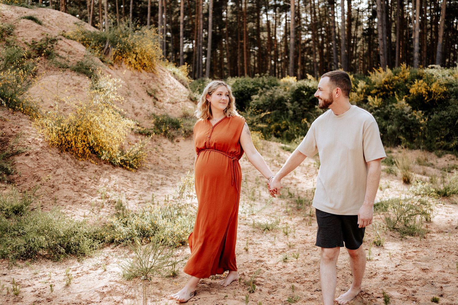 Schwangere Frau und ihr Mann spazieren barfuß durch die Natur bei Spalt. Authentische, natürliche Babybauchfotos voller Emotionen und Nähe.