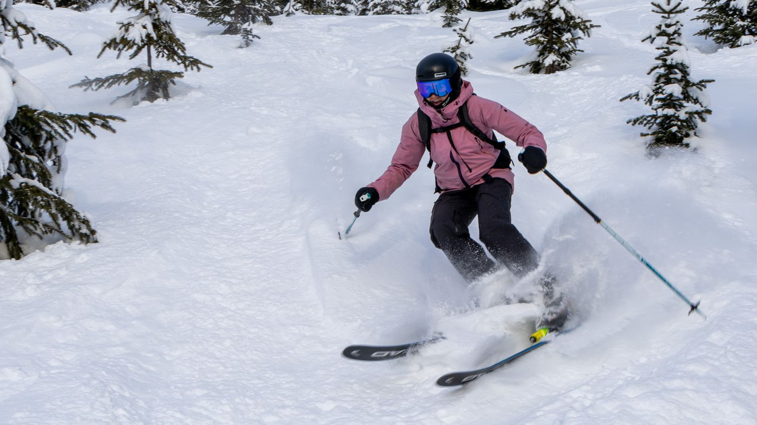 Skier creating powder spray while navigating through snowy terrain on a winter mountain slope.