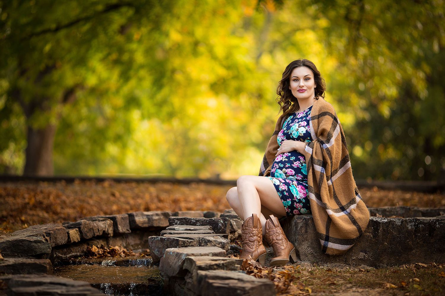 Lifestyle photoshoot in autumn woods with trees casting warm golden light through leaves creating artistic ambiance.
