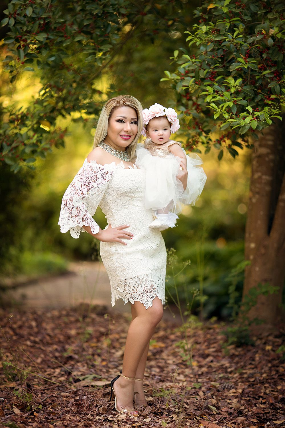 A beautiful white lace dress adorns two figures in a dreamy autumn forest setting with golden bokeh lighting.