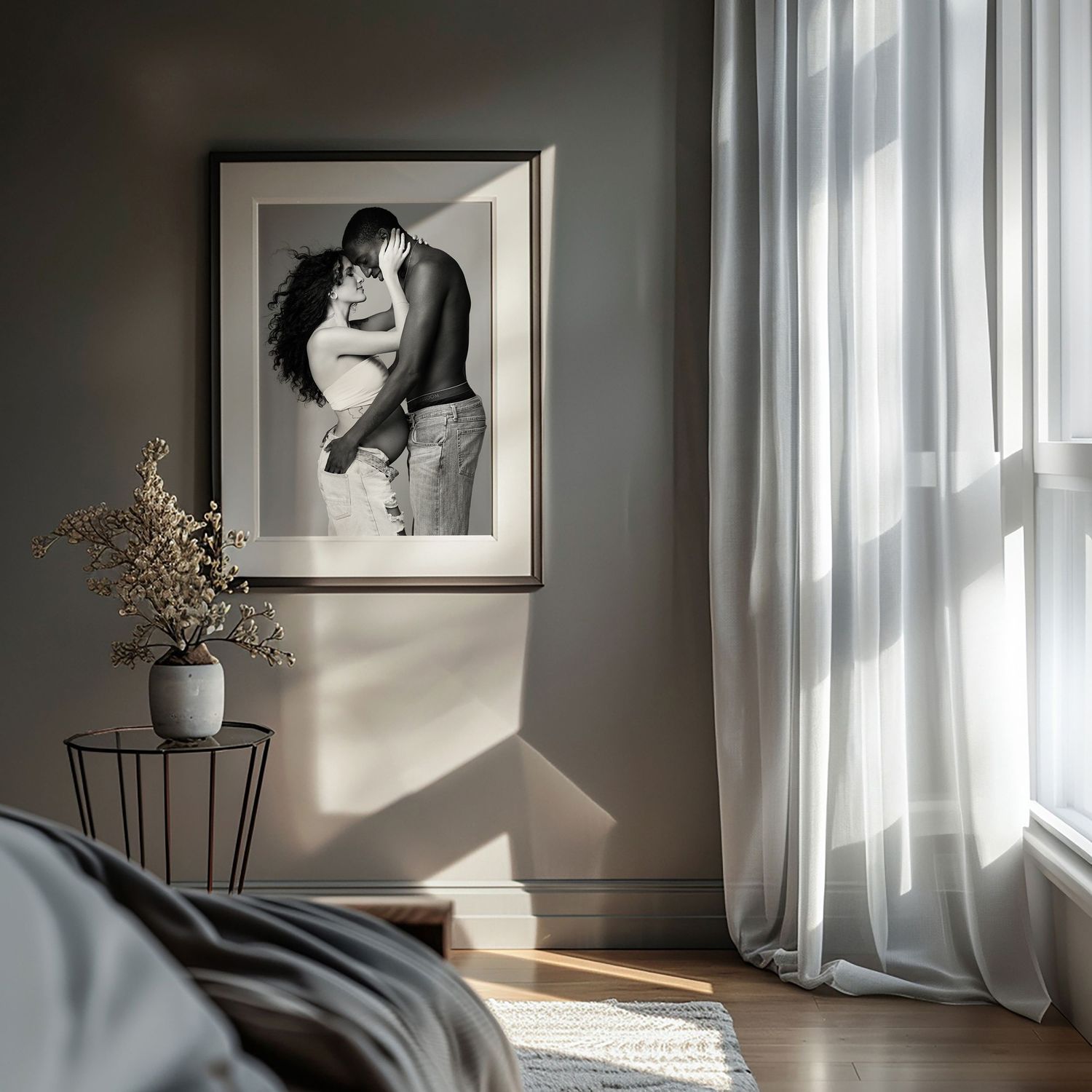 A black and white romantic photograph hangs on a gray wall beside sheer curtains and a small potted plant by the window.