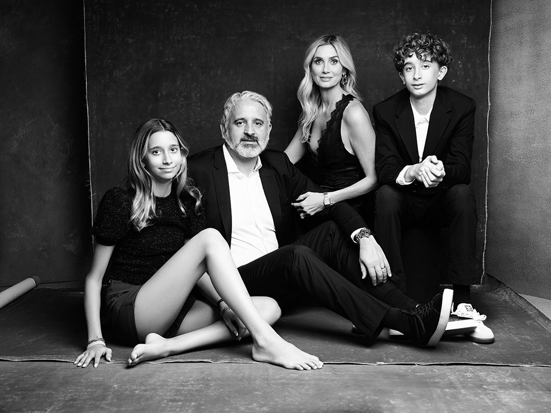 Black and white studio portrait showing a stylish family group in casual poses against a dark background.