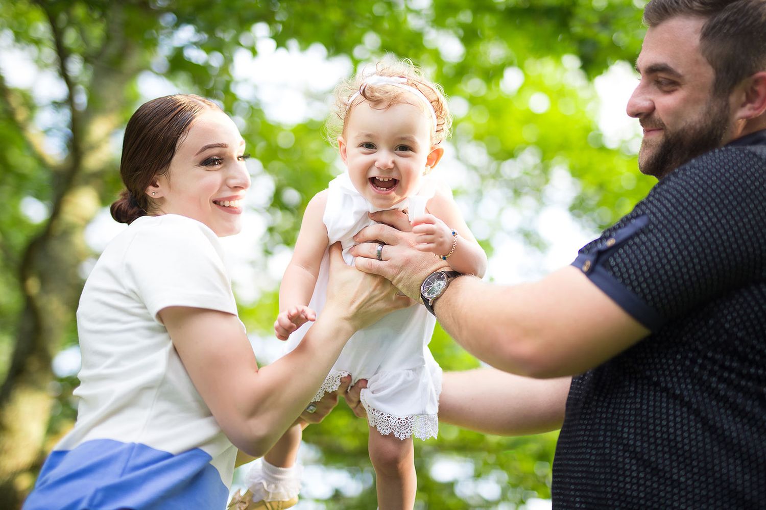 A joyful outdoor family moment captured in multiple candid poses showing connection and laughter against green foliage.