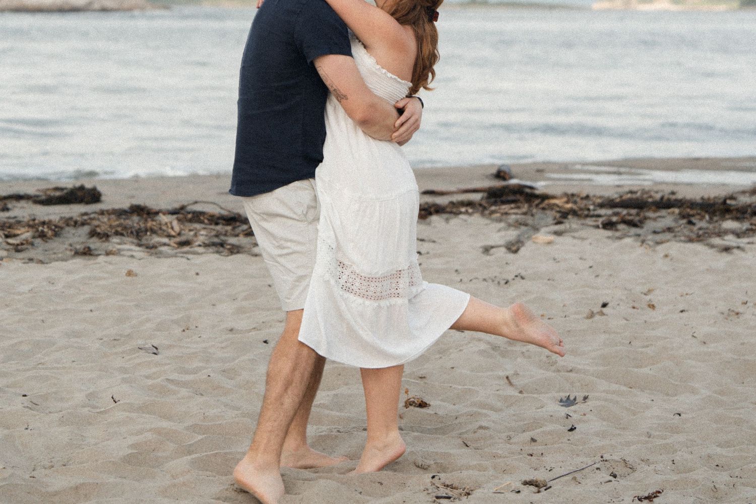 Couple embracing during their engagement session at Popham Beach in Maine