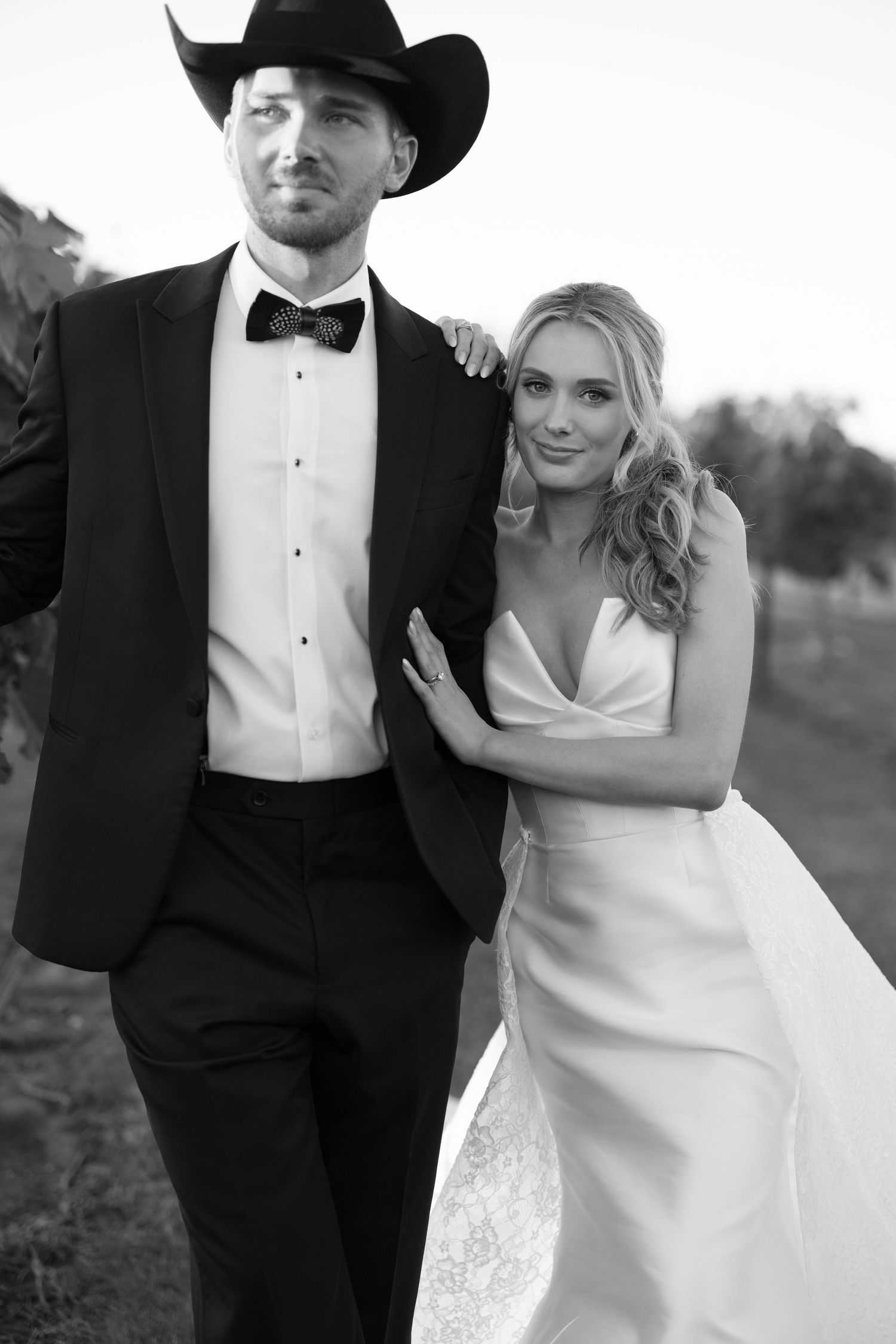 Black and white wedding photo series showing smiling couple in formal attire with cowboy hat outside.