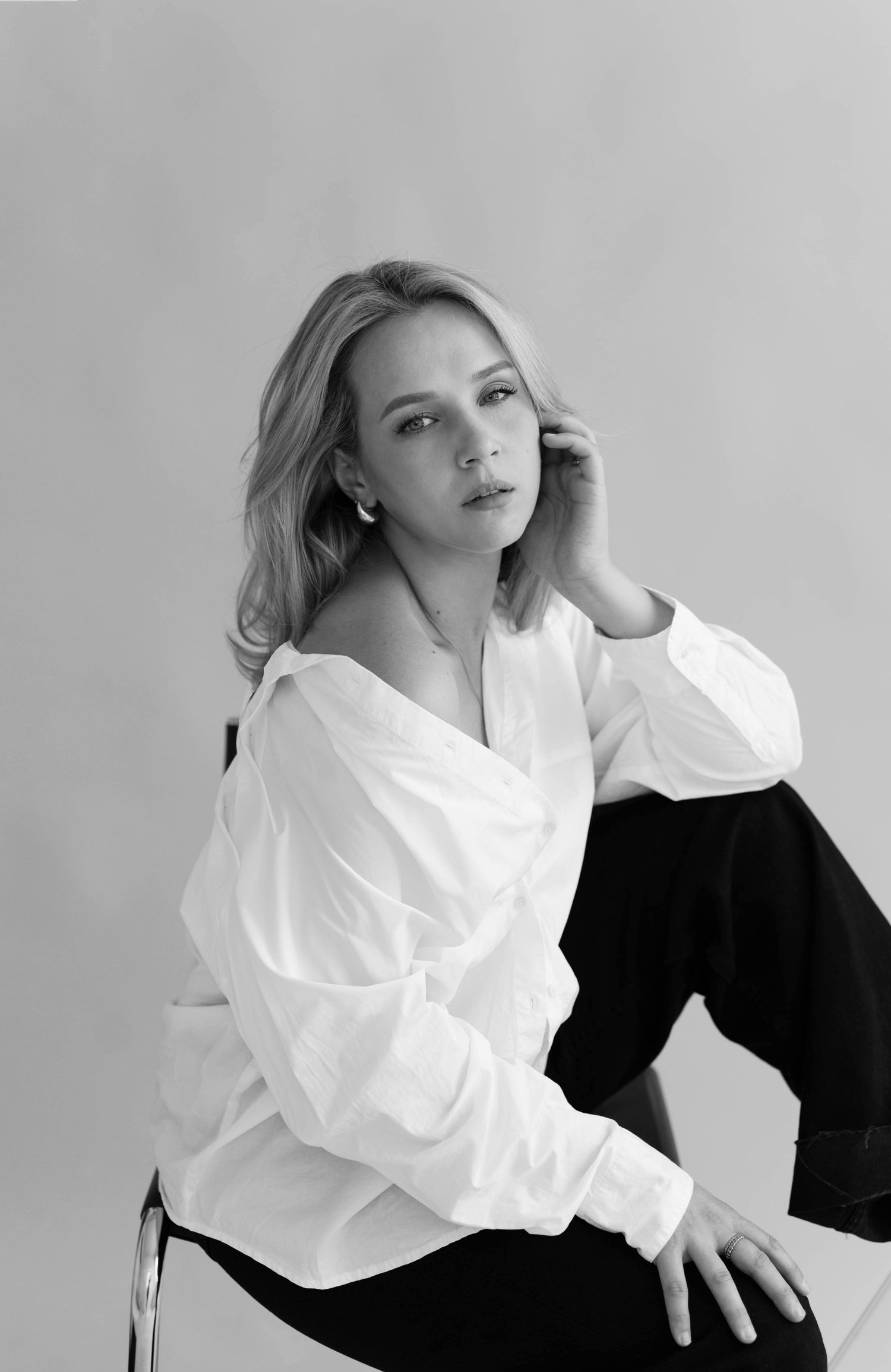 Artistic black and white fashion portraits featuring contrasting white blouse and black attire in minimalist studio setting.