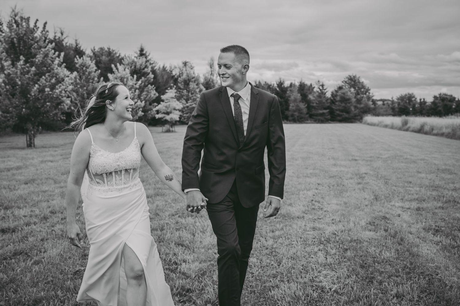 A black and white photo of a couple walking together across an open field.