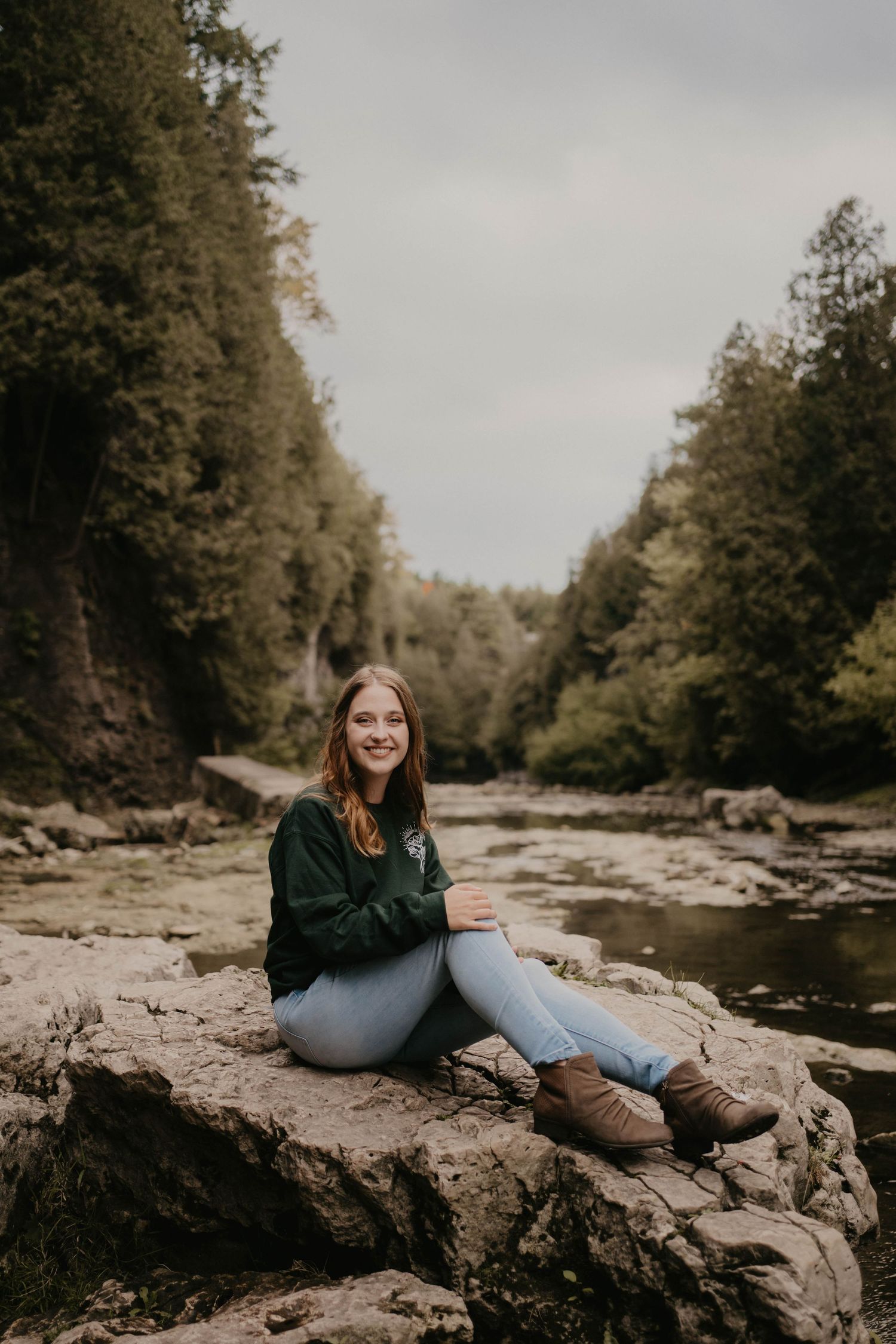 A scenic photoshoot by a rocky riverbed surrounded by autumn trees.