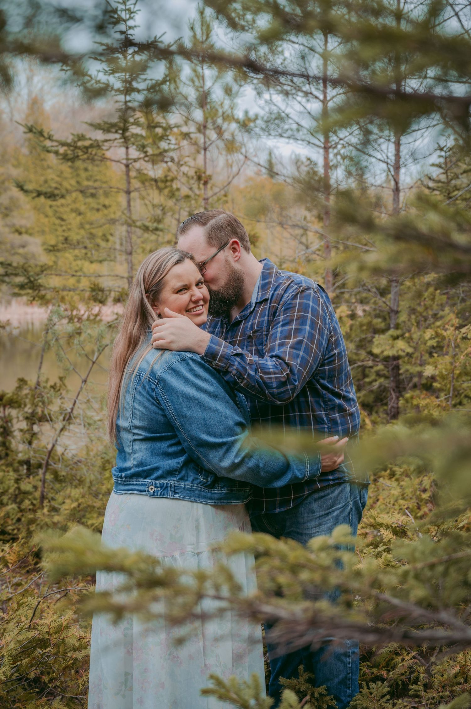 Couple embracing and laughing together on a wooded trail during autumn.