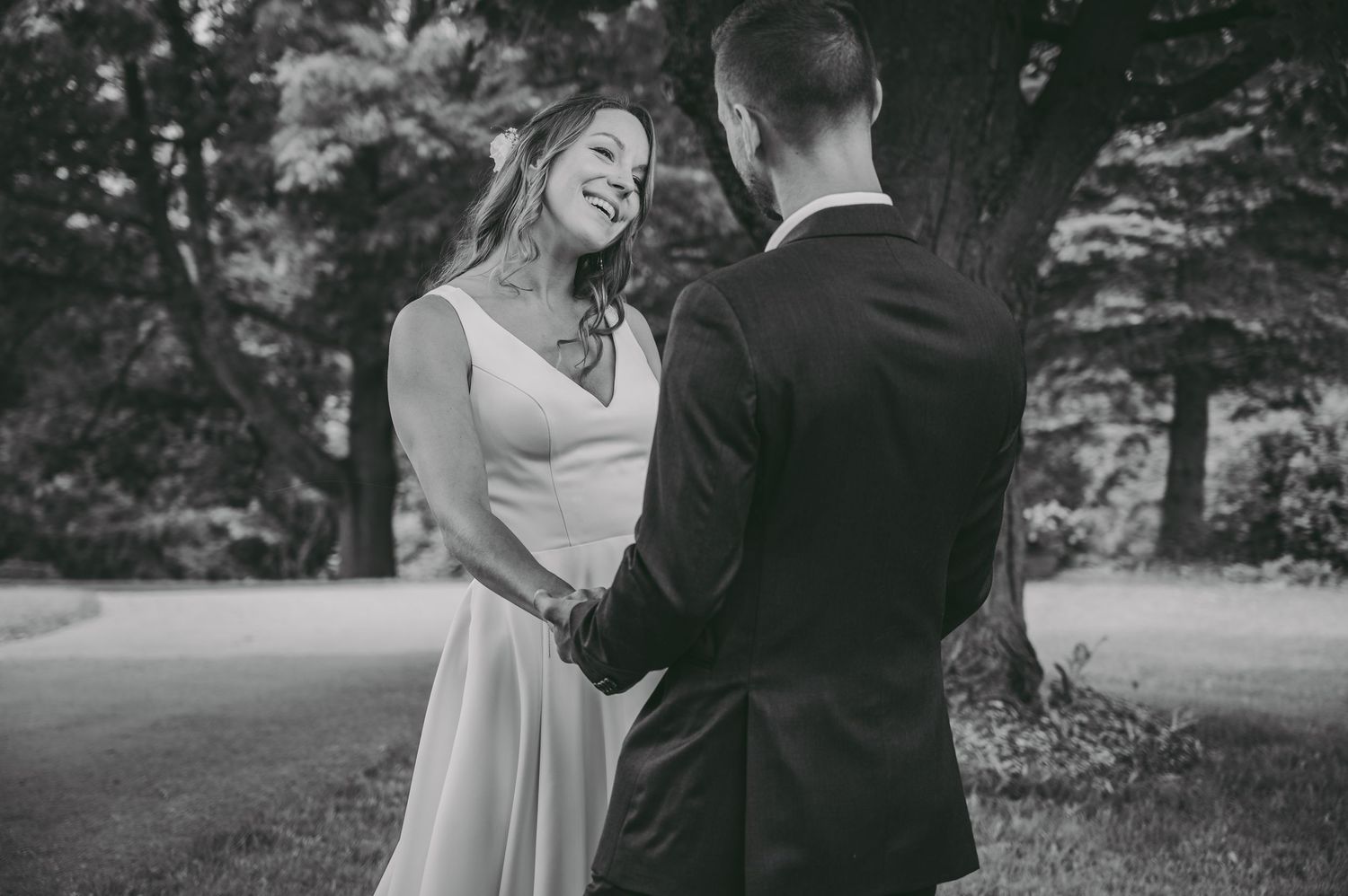An intimate black and white wedding portrait captured outdoors in a garden setting.