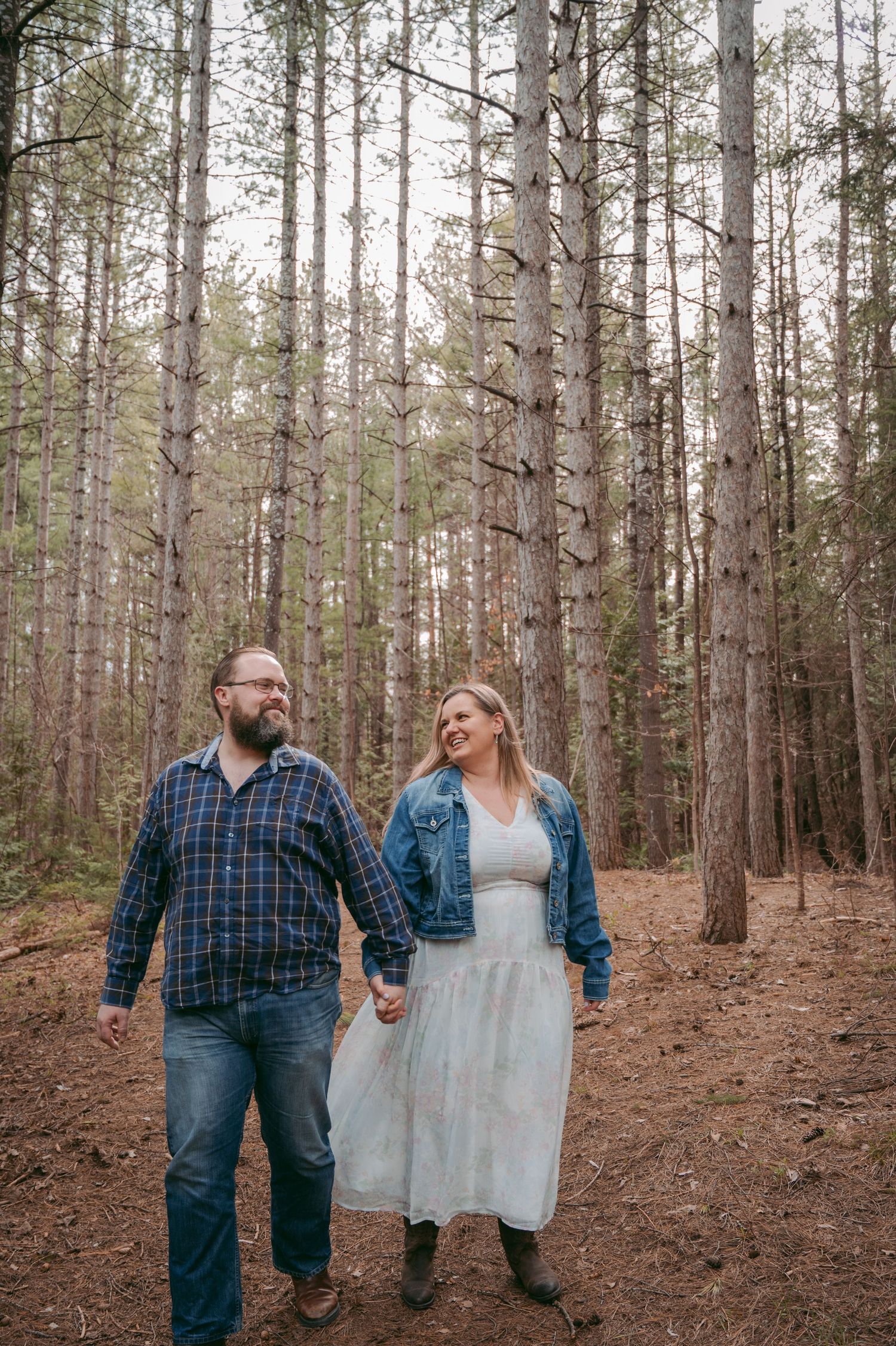 Romantic couple photoshoot among tall pine trees in woodland setting.