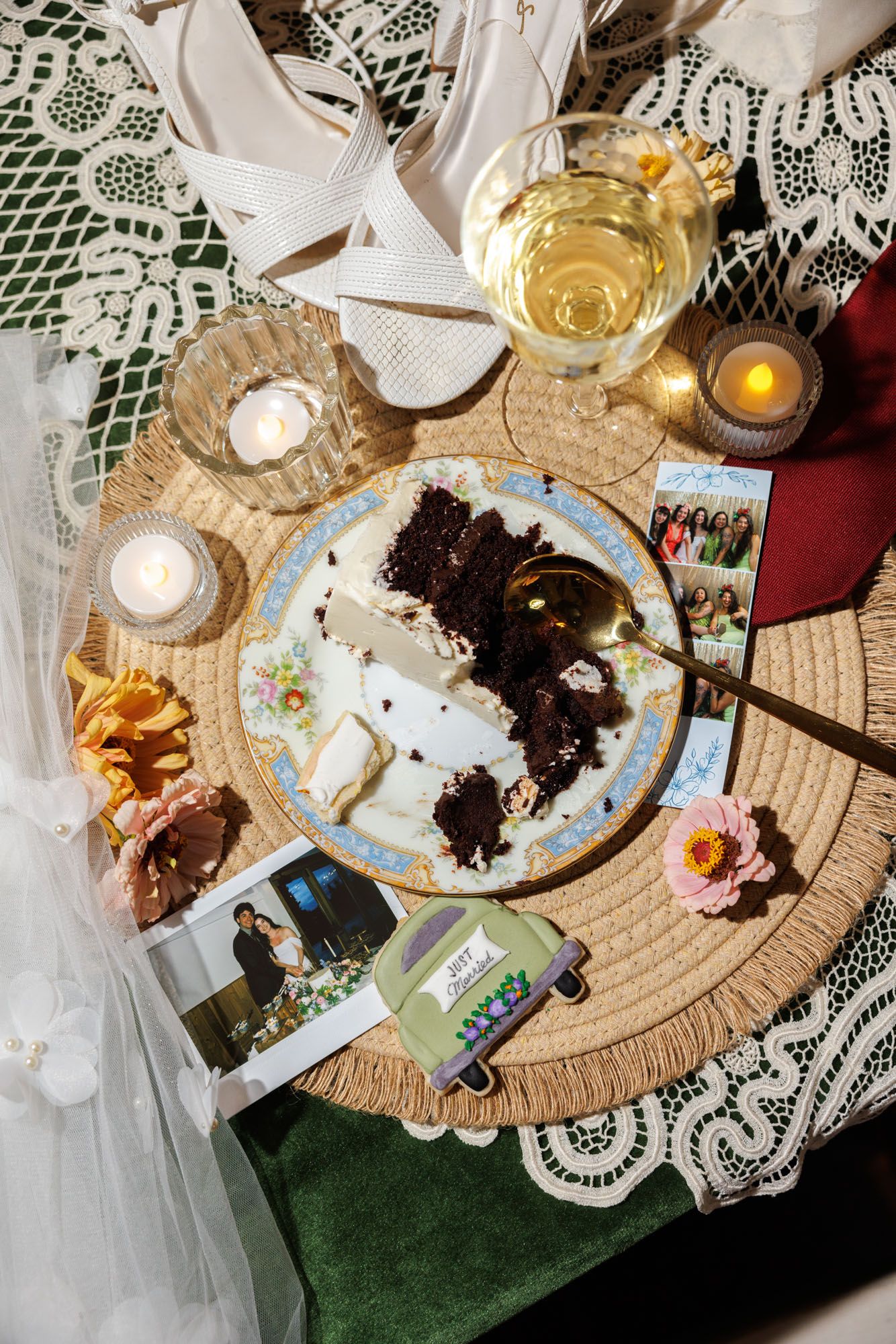 Wedding reception details with partially eaten cake, champagne, and polaroid photos on lace tablecloth.