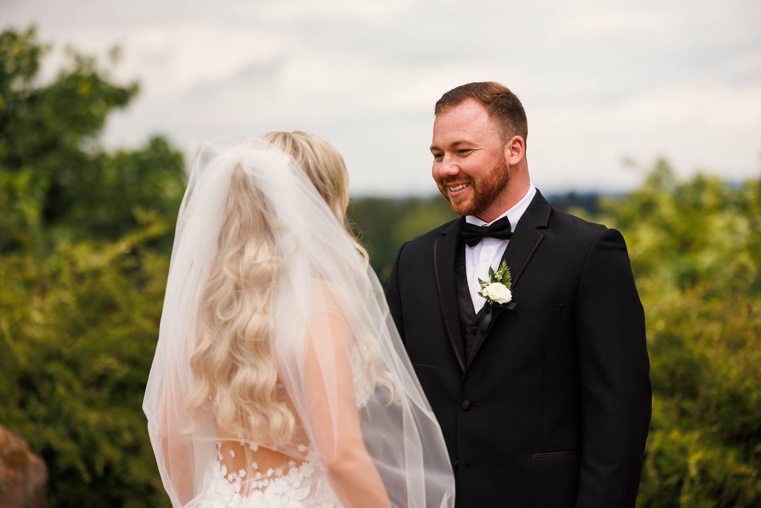 A tender moment during an outdoor wedding ceremony with greenery in background.