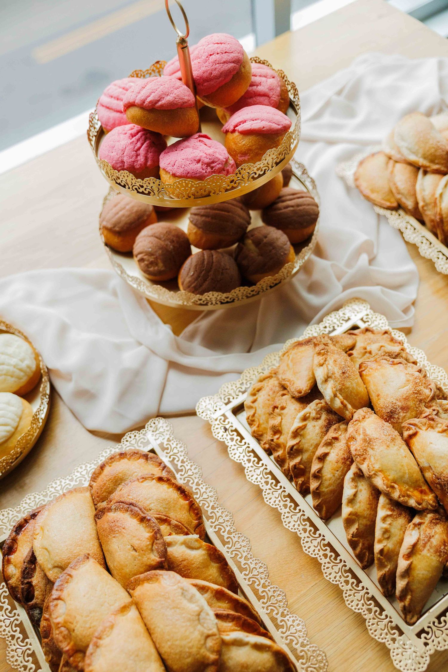 Elegant dessert display featuring pink macarons and pastries on ornate gold serving platters.