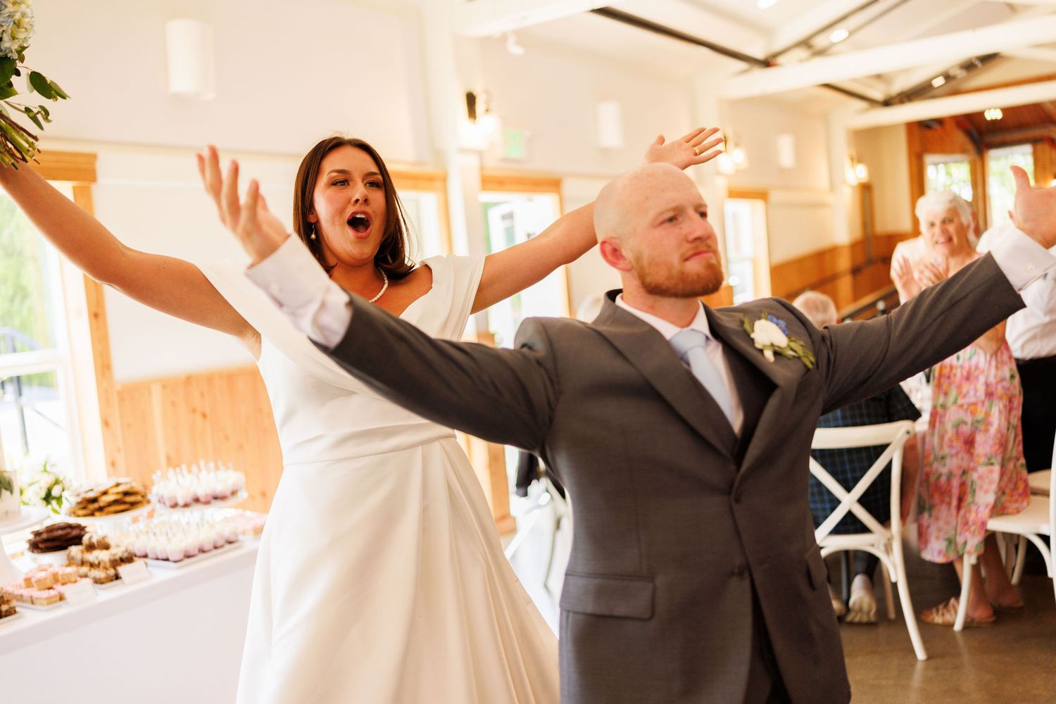 Wedding guests celebrating with arms raised in joyful celebration indoors.