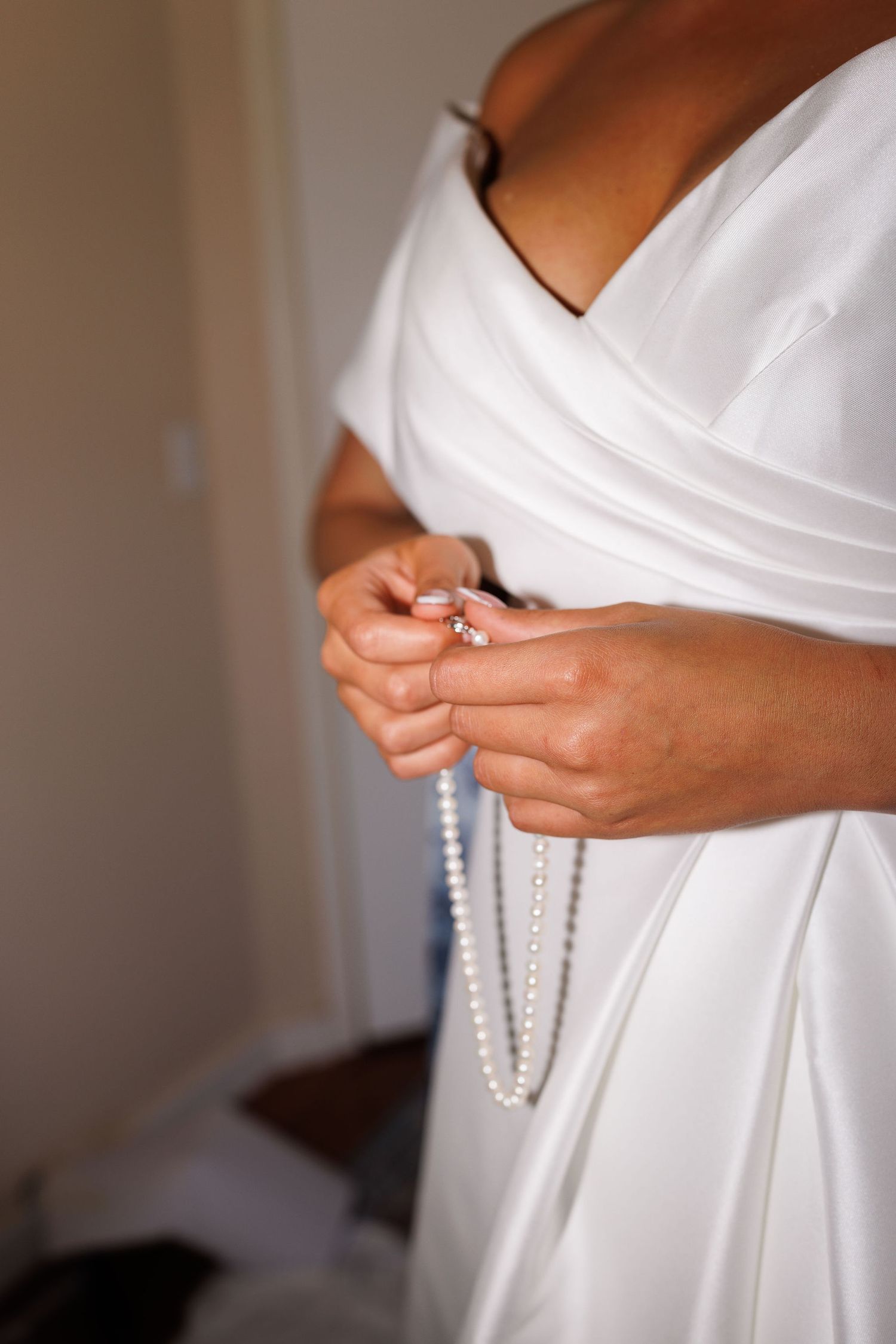 Close-up details of white wedding dress folds and pleating.