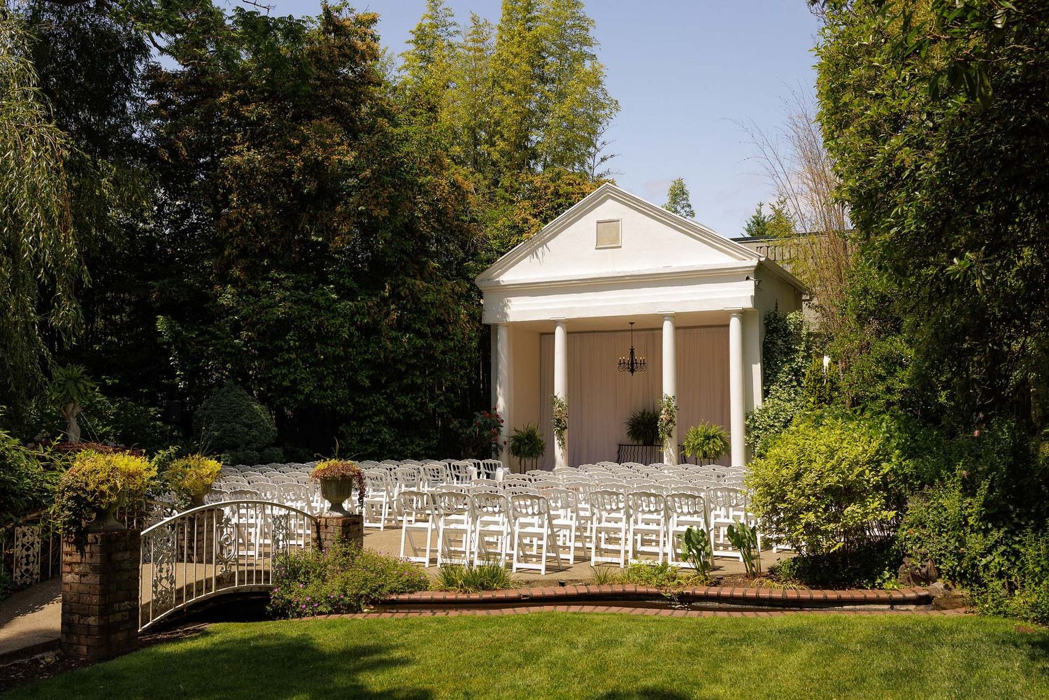 White colonial-style wedding venue with pillars and white chairs set up for outdoor ceremony.