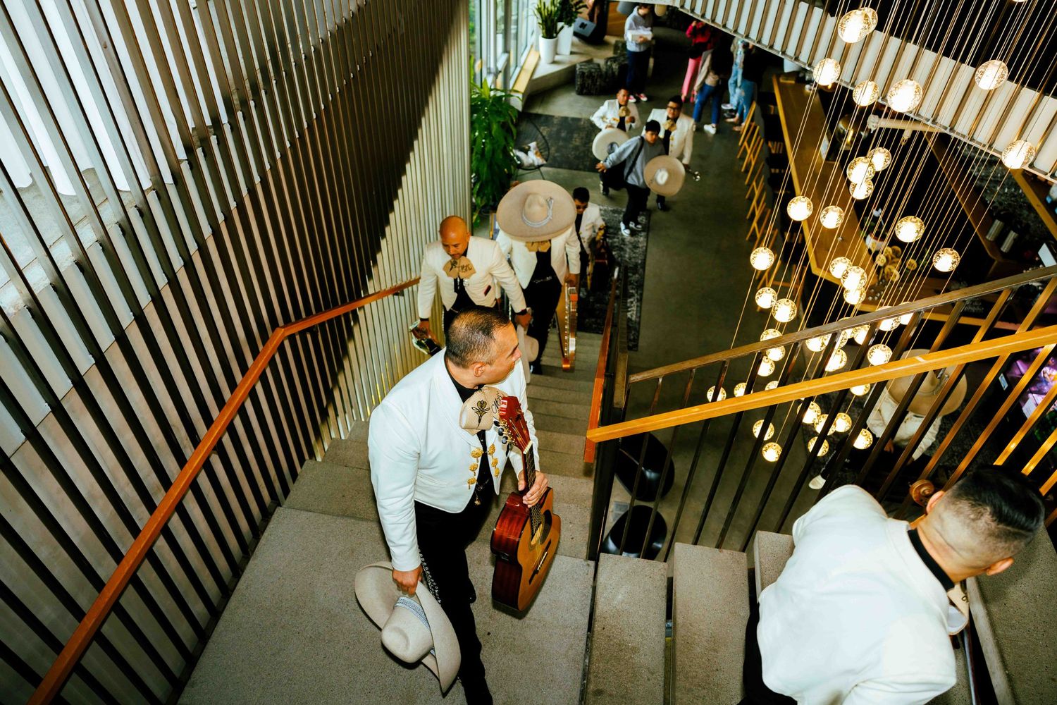 Wedding guests descending modern staircase with industrial lighting design.