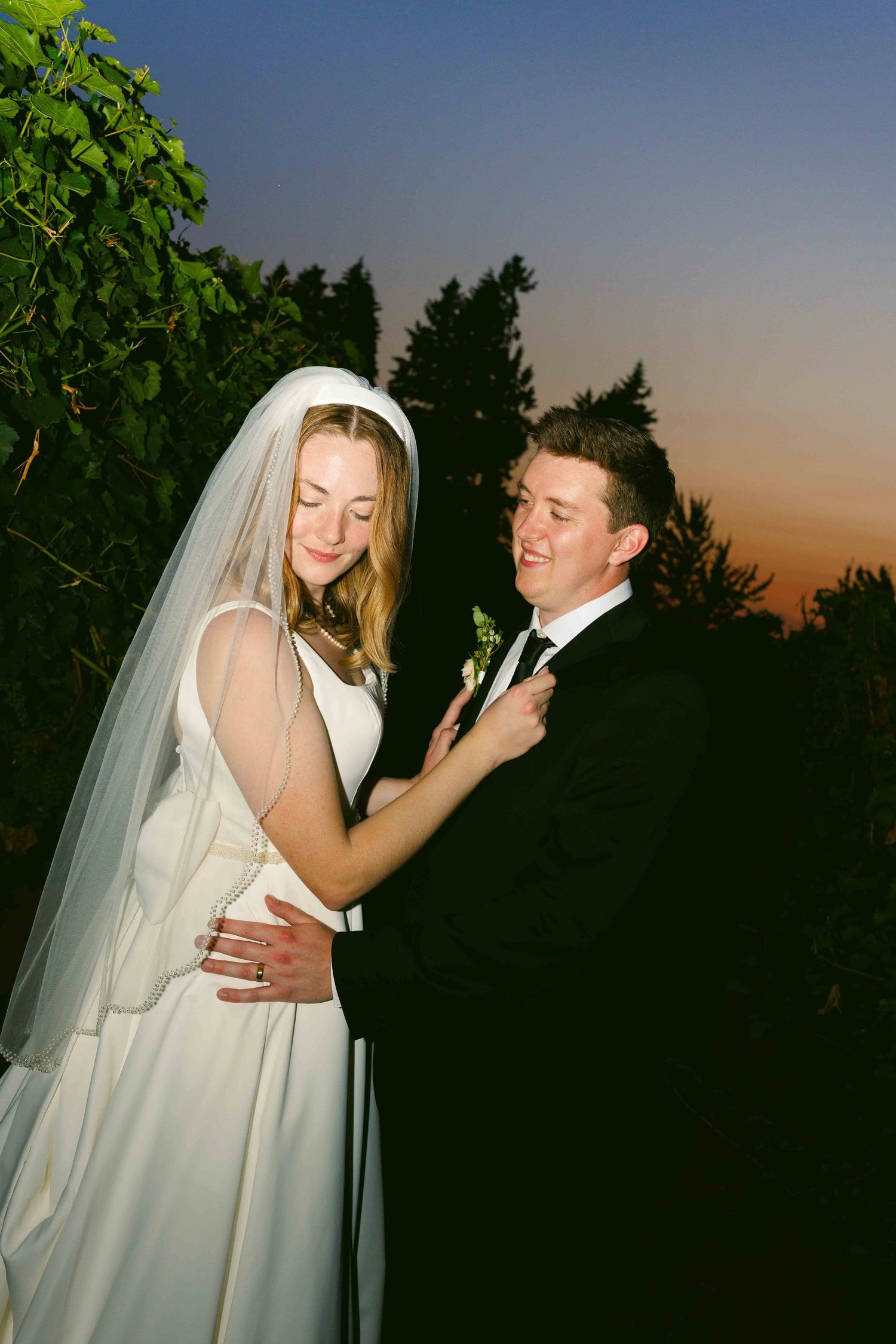 Romantic sunset portrait of bride and groom sharing intimate moment outdoors.