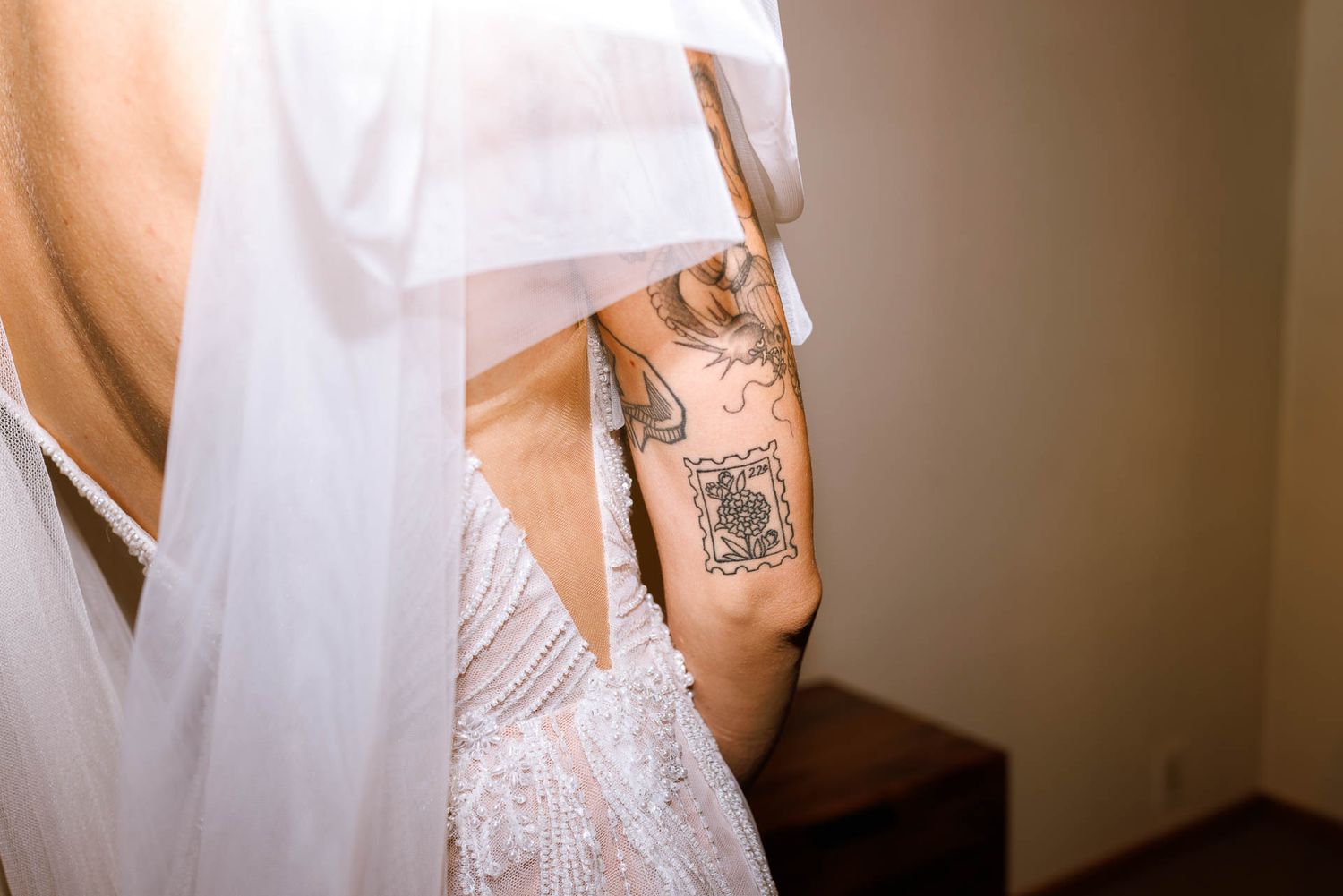 Close-up detail of a white wedding dress with a tattoo visible underneath.