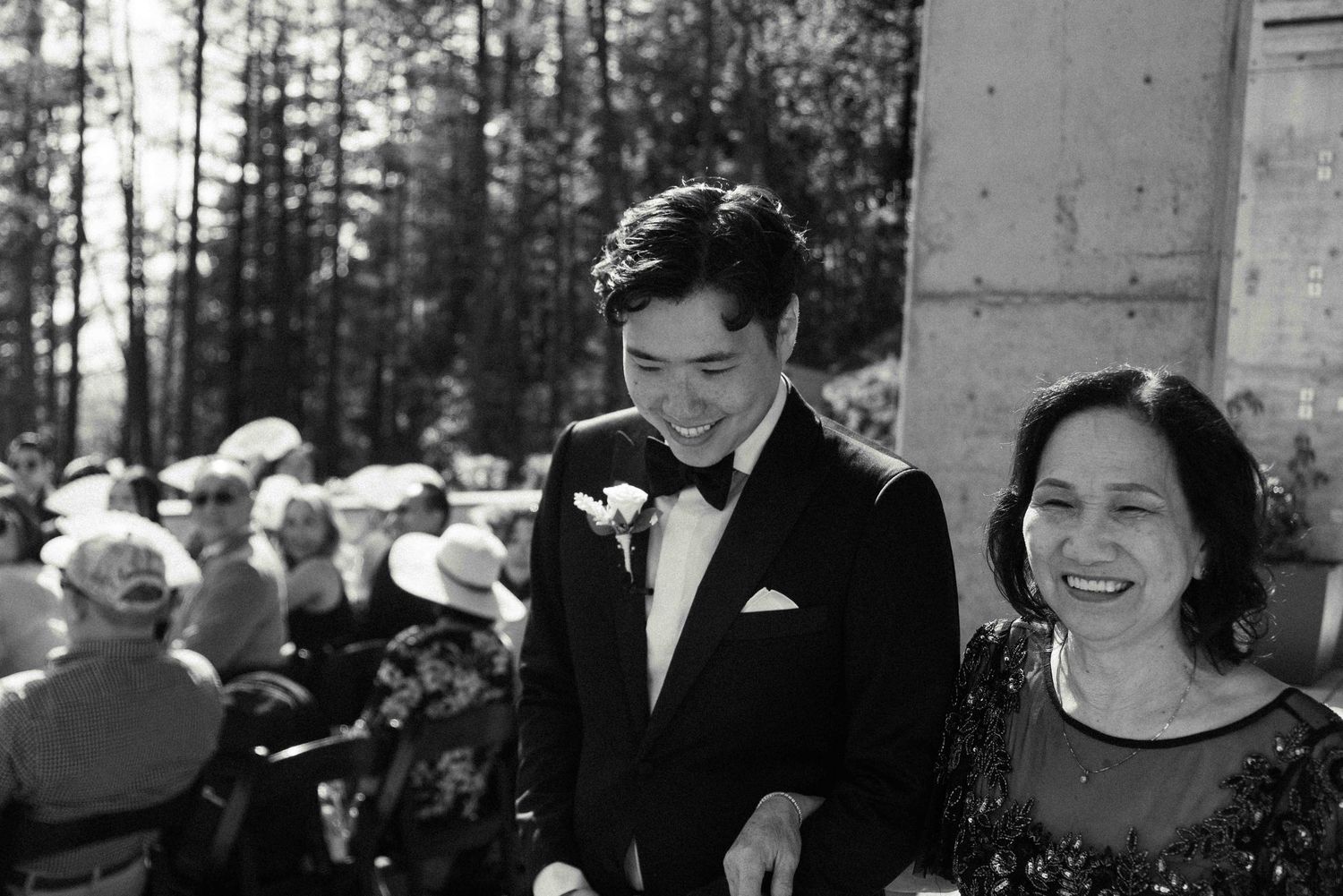 Black and white candid moment of joy during outdoor wedding ceremony.