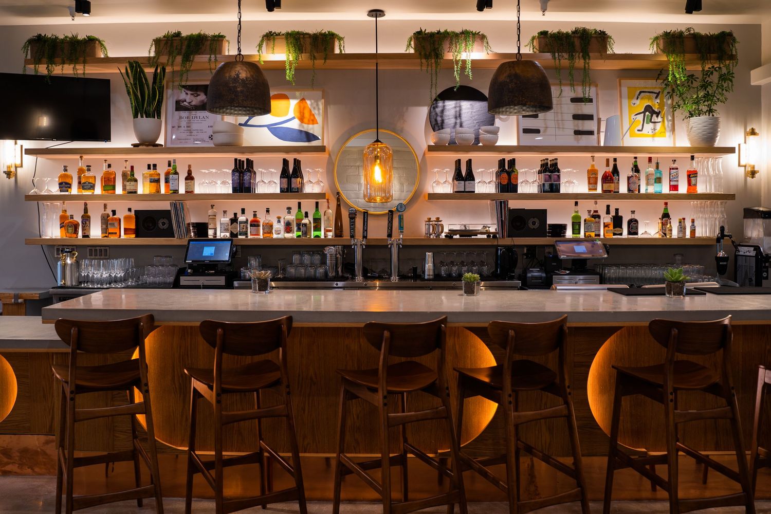 Moody interior bar scene at California pizzeria with low lighting and glowing shelves of spirits