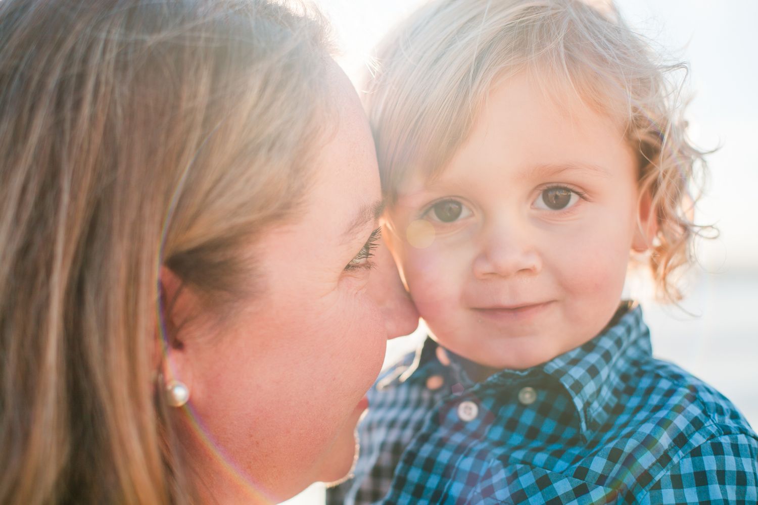 Tender beach moment between mother and child wrapped in an embrace – natural light family photography